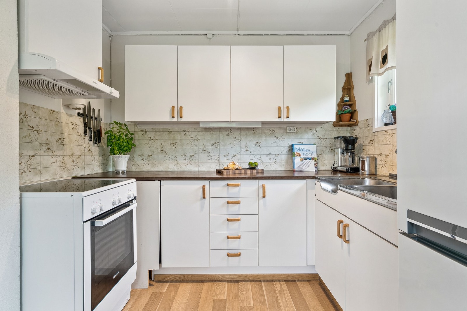 Kjøkkenet har slette fronter på innredning og laminat benkeplate - Frittstående hvitevarer Galleribilde