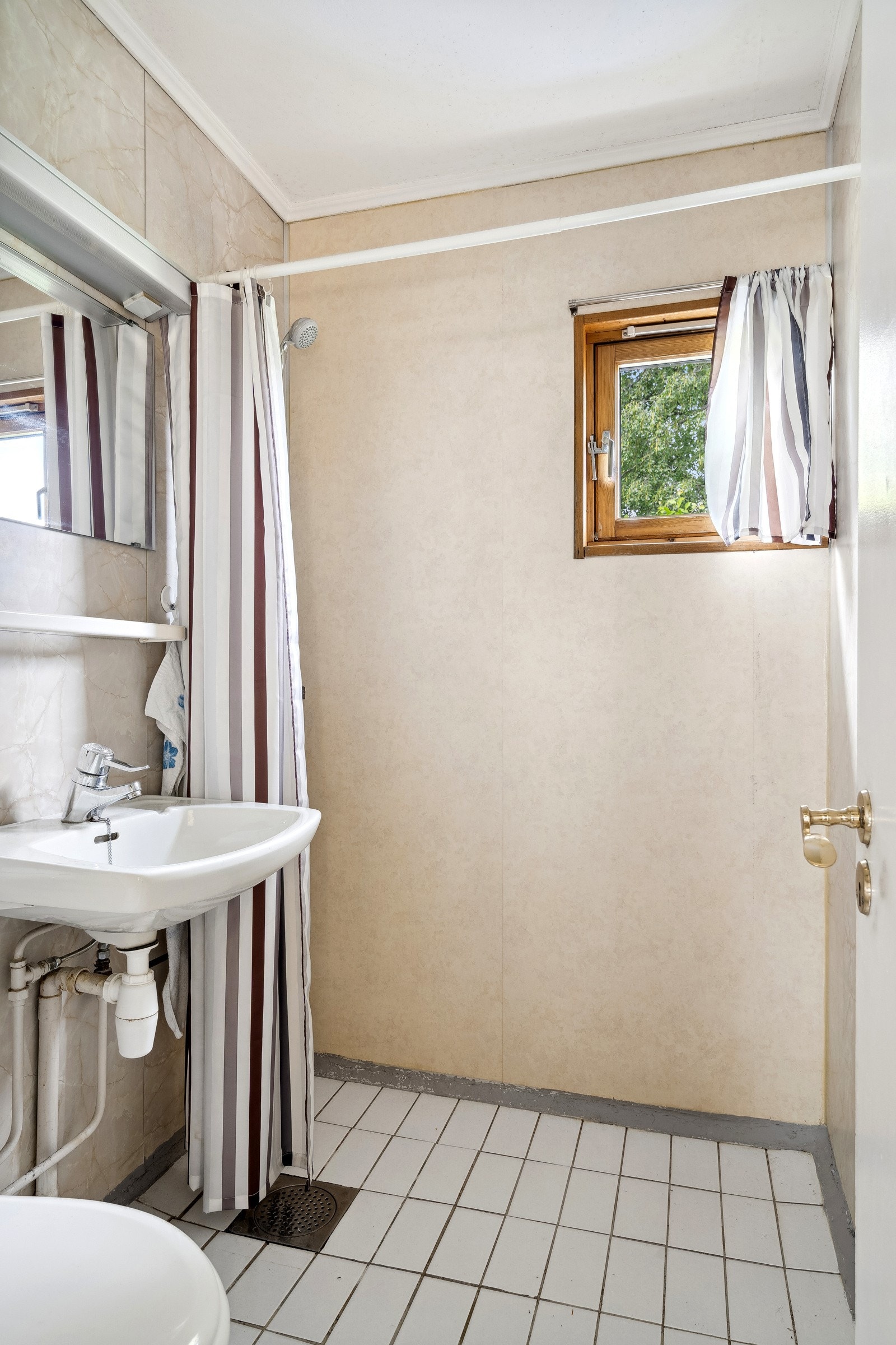 Badet har flis på gulv og baderomsplater på vegg. Galleribilde