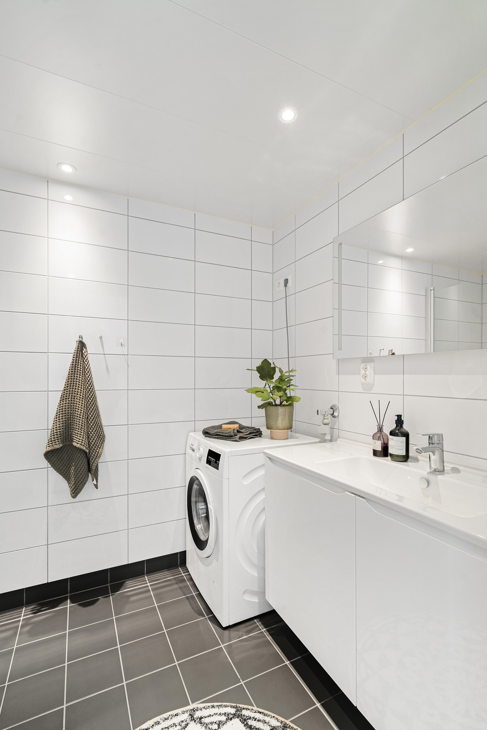 Lys baderomsinnredning med speil over innredningen. På badet er det opplegg for vask/tørk.