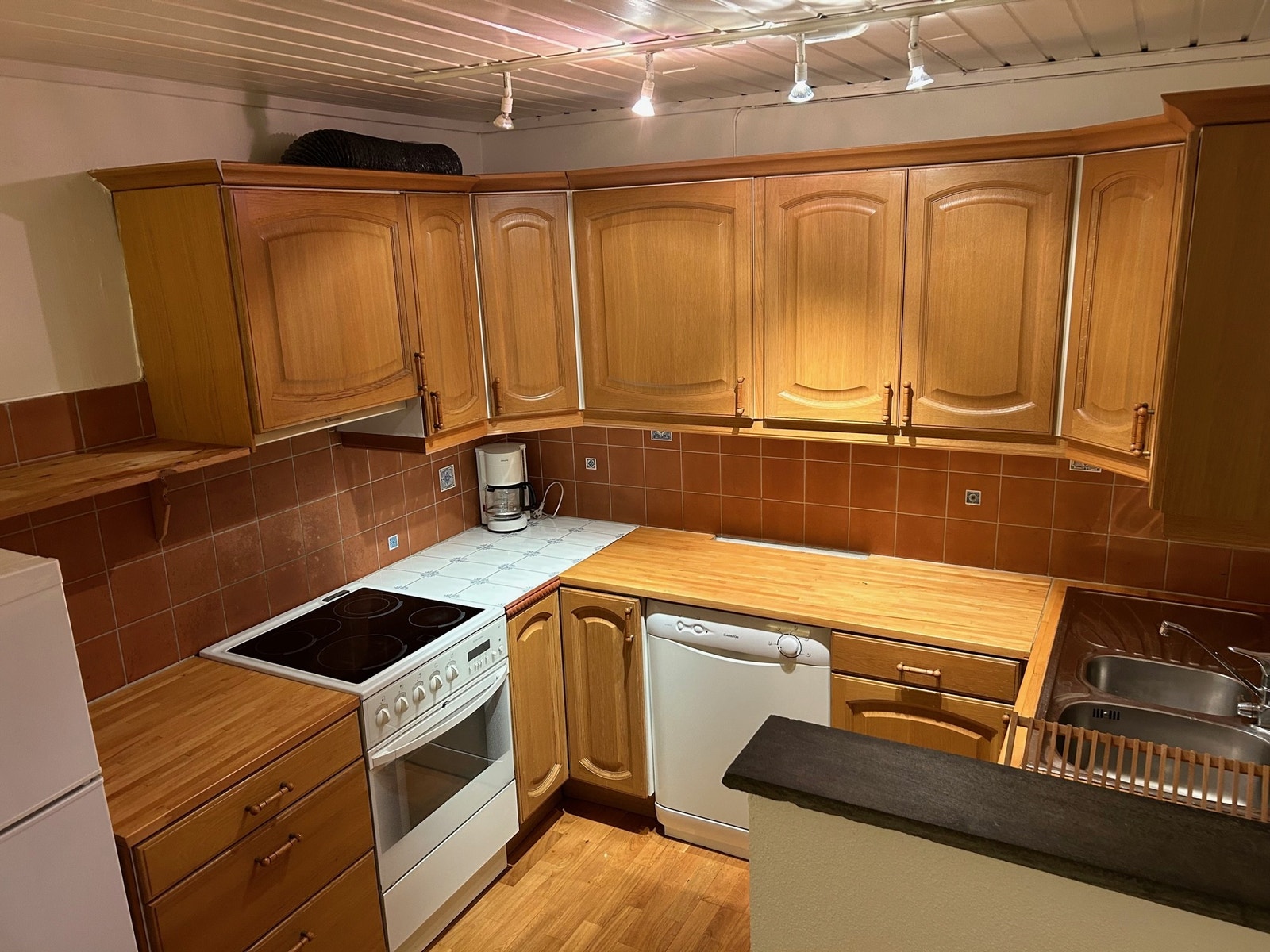 Åpen kjøkkenløsning med komfyr, kjøl/frys og oppvaskmaskin Galleribilde