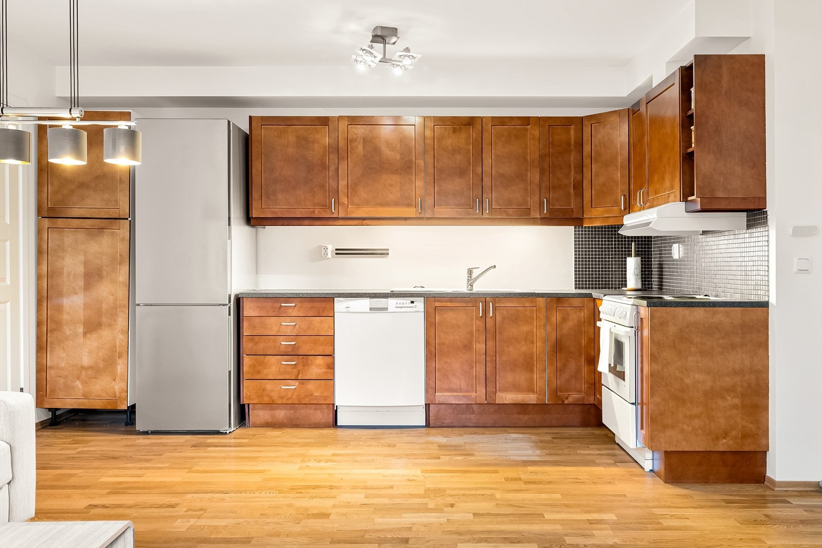 Norema kjøkkeninnredning med profilerte fronter. Veggen bak kokesonen er flislagt med mosaikkfliser som gjør renholdet enkelt. Galleribilde