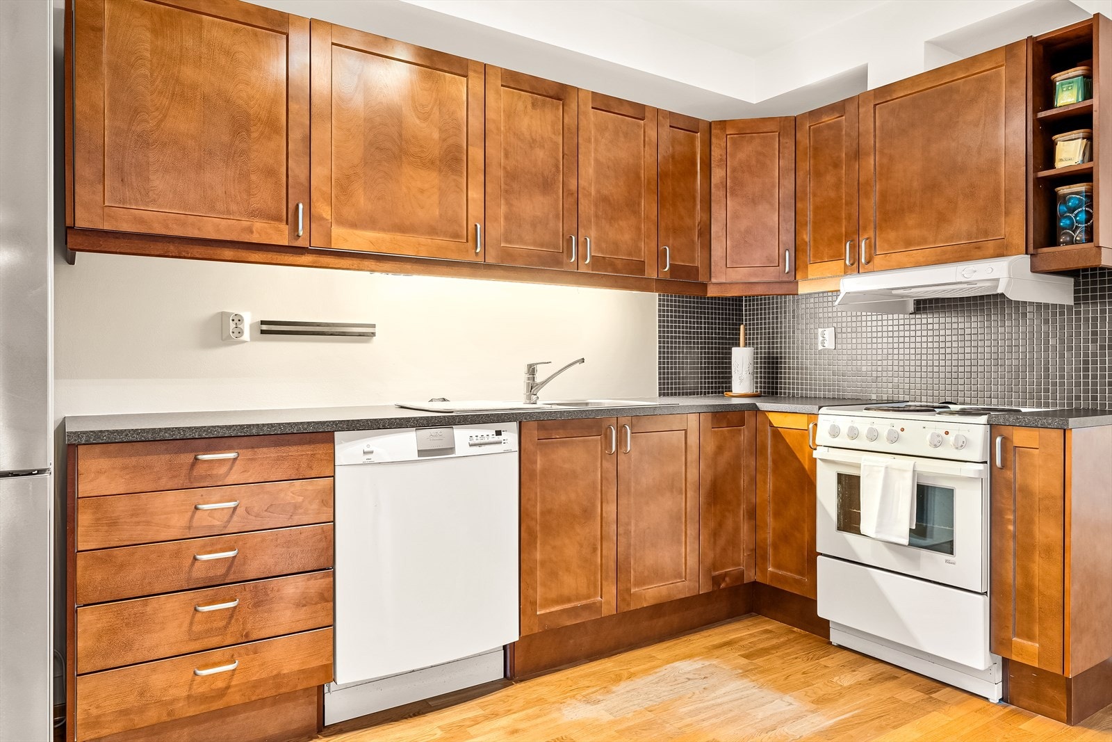 Kjøkkenet inneholder: laminat benkeplate, stål vaskekum, ventilator og opplegg for oppvaskmaskin. Medfølgende hvitevarer: Komfyr og oppvaskmaskin. Galleribilde