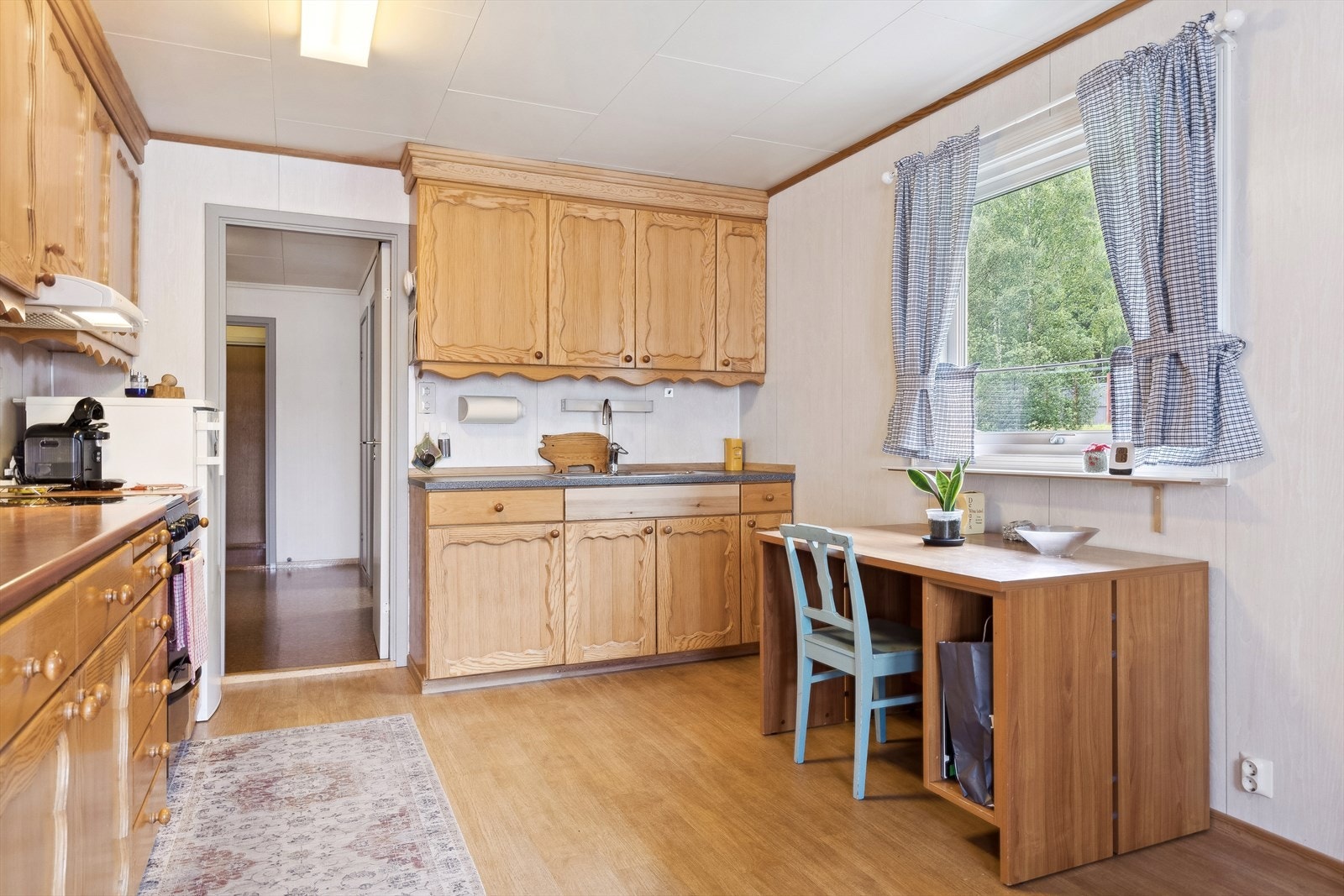 Innredning med laminat benkeplate, ellers er det heltre med lakkede fronter. Nedfelt stålkum, opplegg komfyr med ventilator over. Galleribilde