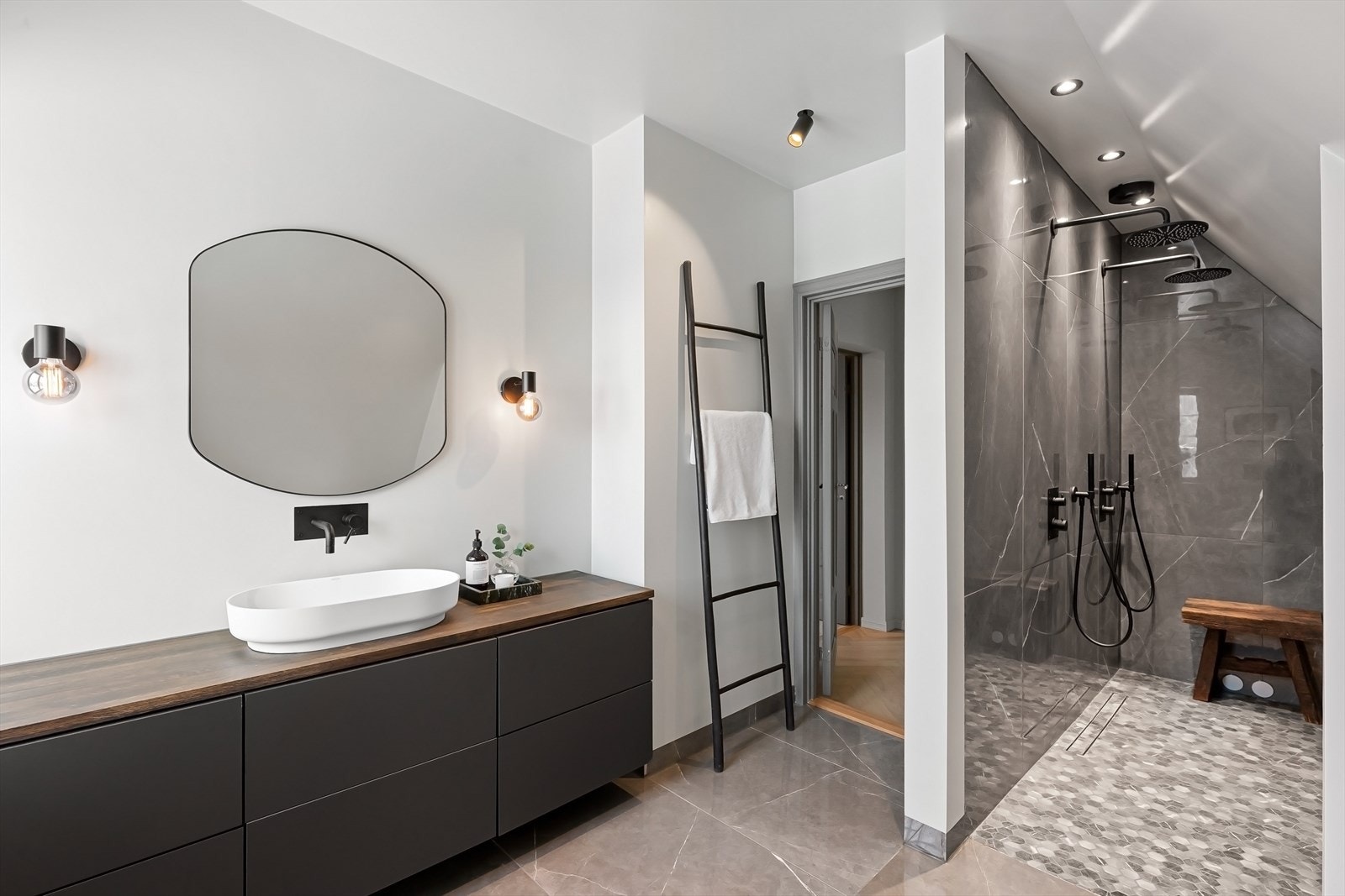 Badet har badekar, servant med skuffer, speil og to regnfallsdusjer. Galleribilde