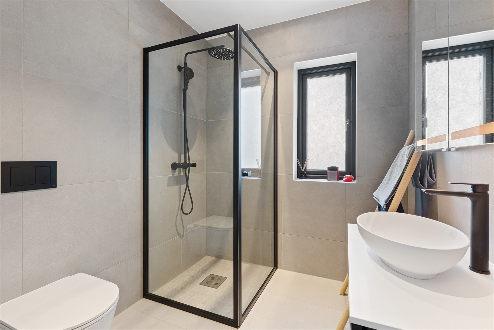 På det andre badet i 1. etasje er det et lekkert dusjhjørne med regnfallsdusj, innfellbare glassdører og sorte detaljer. Galleribilde