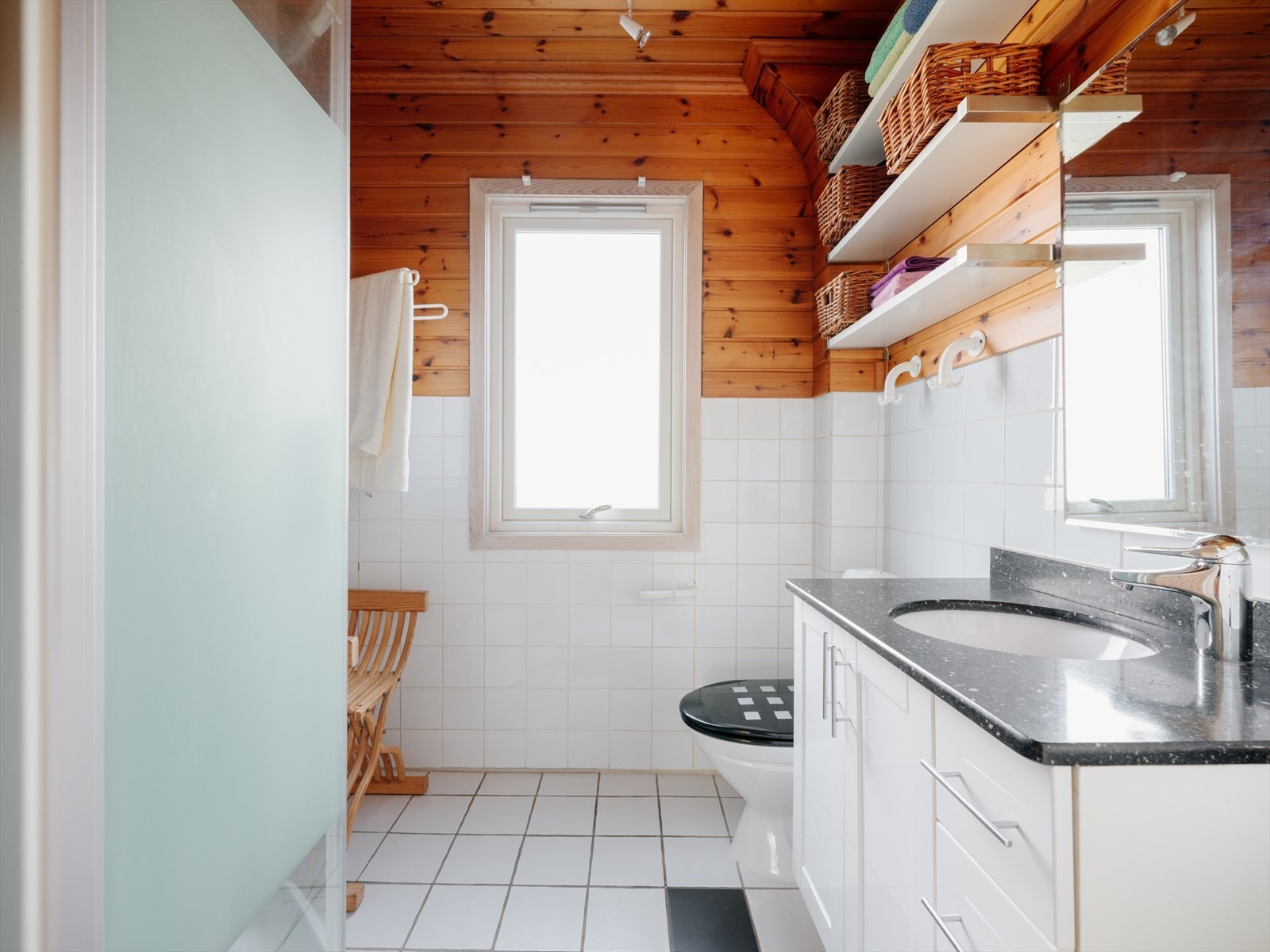 Badet er innredet med servantskap, wc og dusjkabinett. Et greps servantkran. En underlimt kum i stein benkeplate med speil over og hyller. Galleribilde