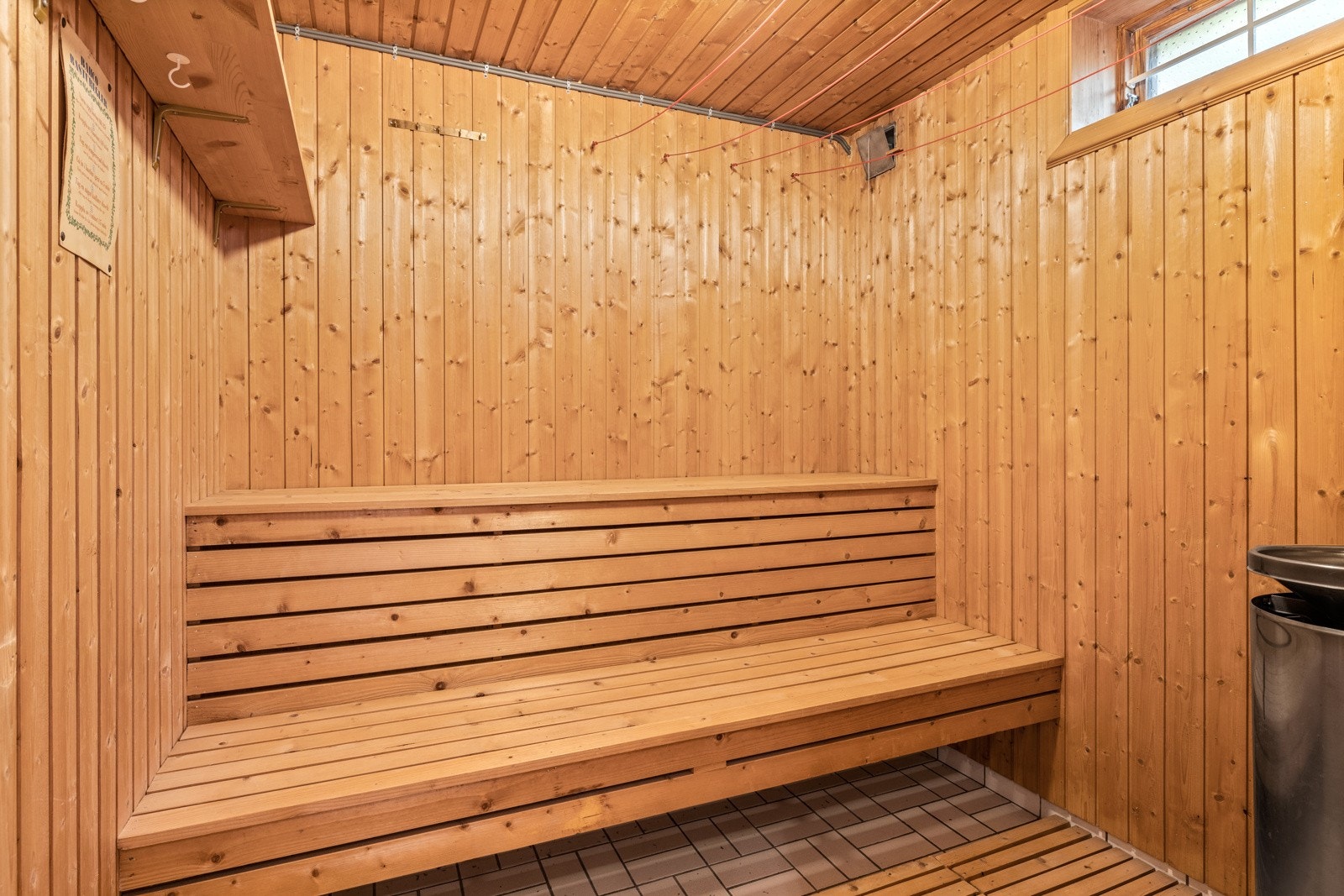 Inngang fra baderom til badstue med tremmer i tre på flislagt gulv og vegger og tak av panel Galleribilde