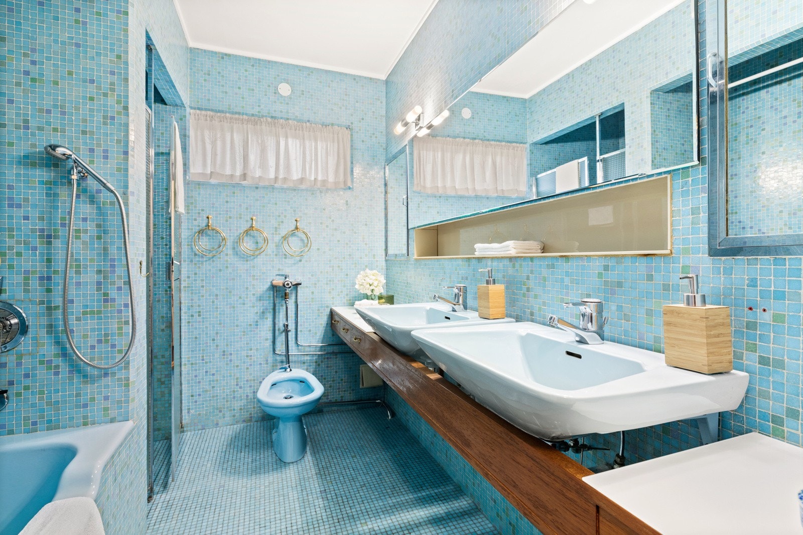 Baderom med to servanter og speil over. Innebygd speilskap og hylle. Mosaikkfliser på gulv og vegger Galleribilde