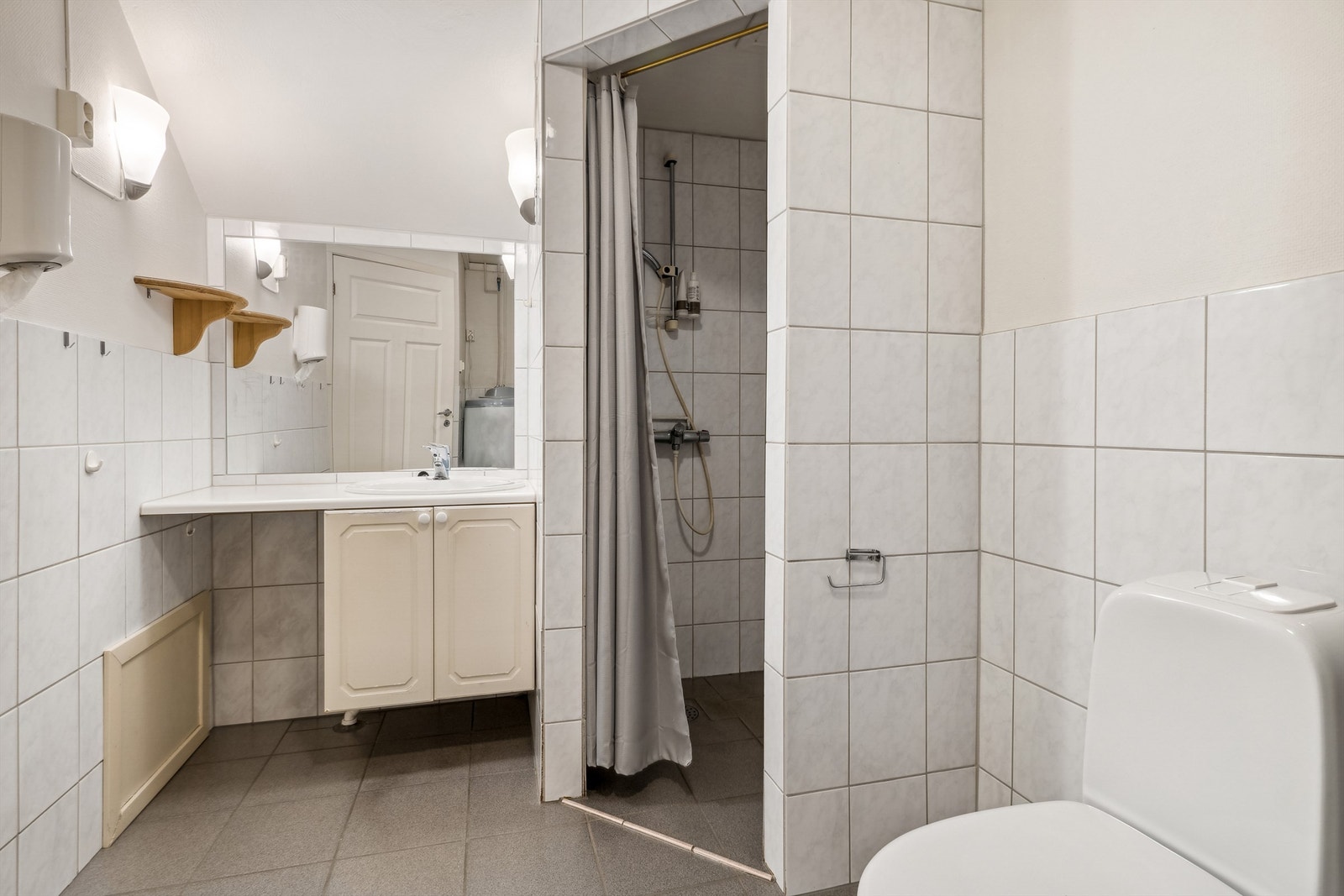 Badet er innredet med baderomsinnredning, speil, toalett, dusjnisje og opplegg for vaskemaskin Galleribilde