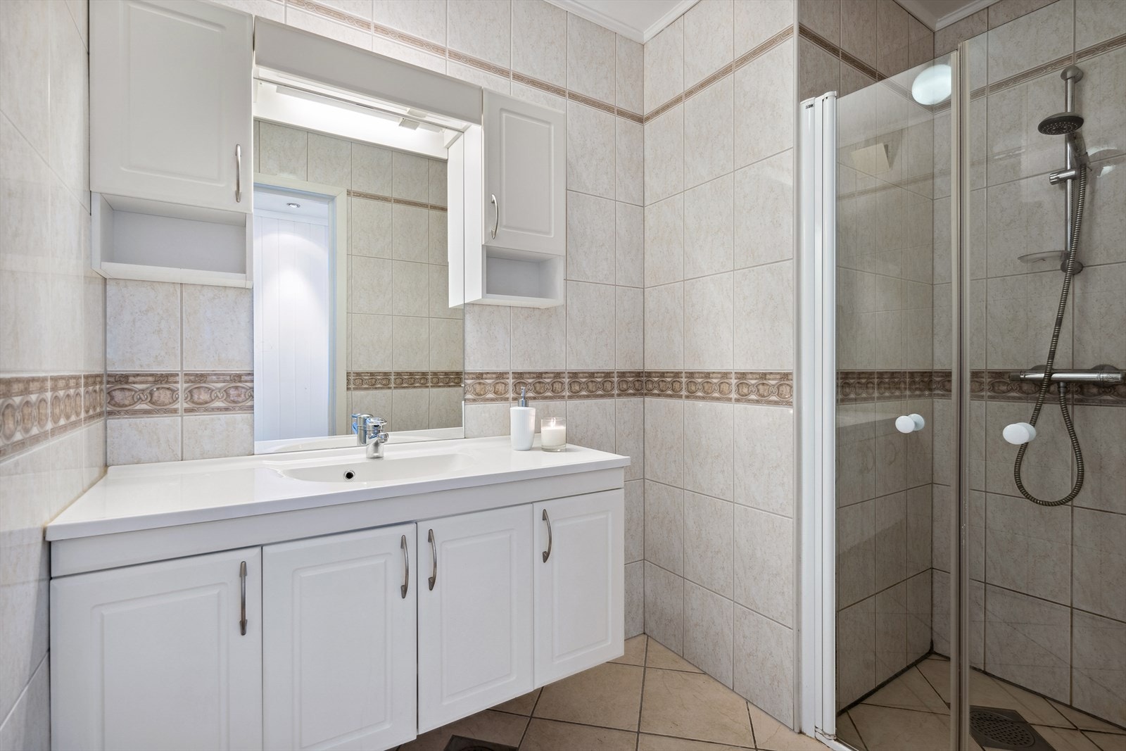 Flislagt bad med varmekabler i gulv, servantskap, wc og svingbare dusjdører. Galleribilde