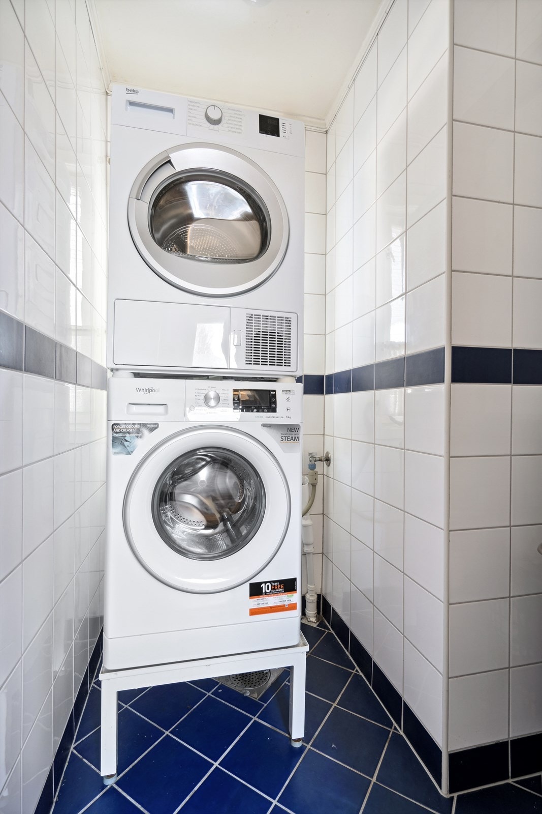 Flislagt vaskerom med sluk i gulv, utslagsvask og opplegg til vaskemaskin og tørketrommel. Galleribilde