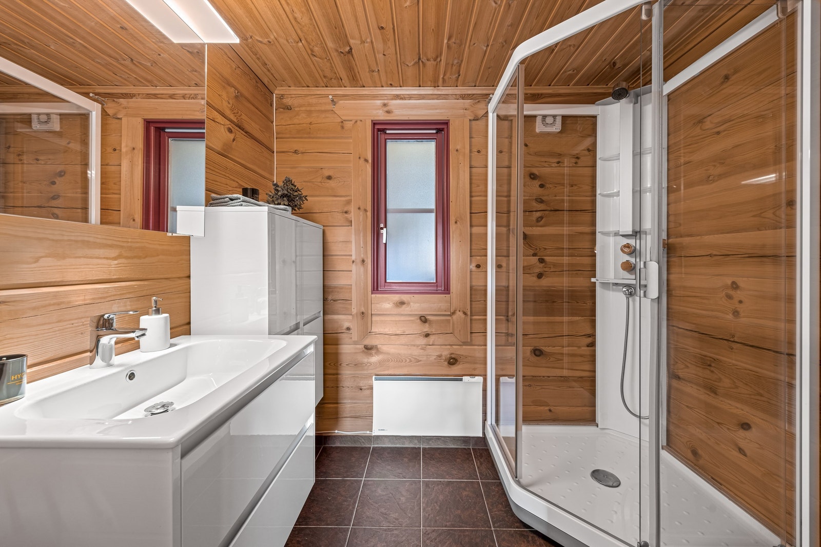 Badet er godt innredet med skaper, servant i innredning, toalett og dusjkabinett Galleribilde