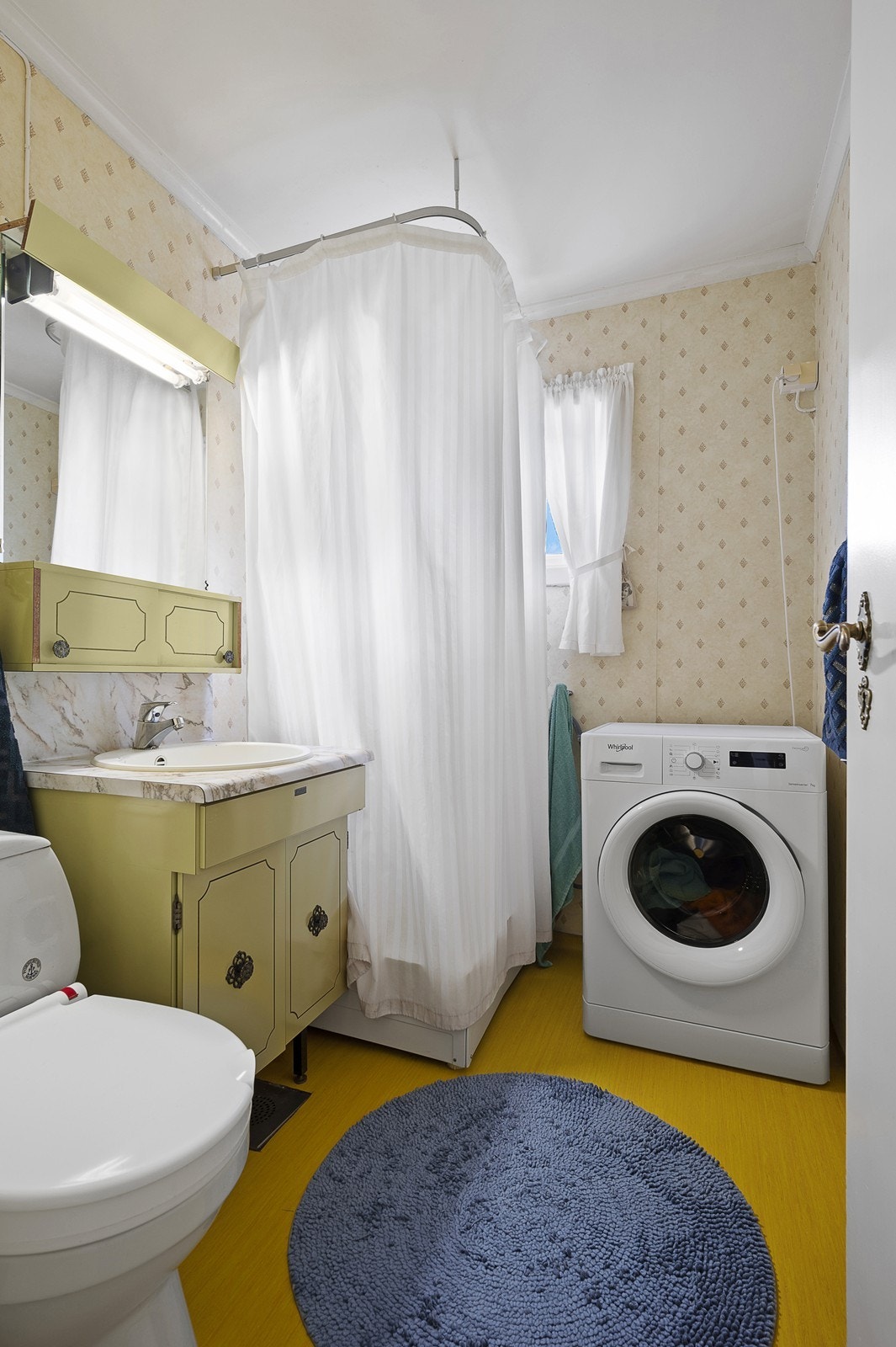 Badet inneholder wc, eldre håndvask med tilpasset skap. Dusjkabinett og opplegg for vaskemaskin. Galleribilde