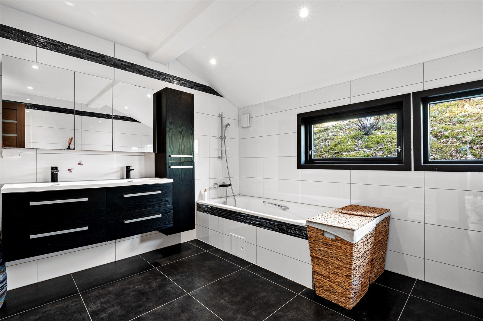 Flislagt bad med varmekabler, downlights, opplegg for vaskemaskin og tørketrommel, speilskap, innmurt badekar, vegghengt toalett, dusj hjørne og dobbel servant med innredning. Galleribilde