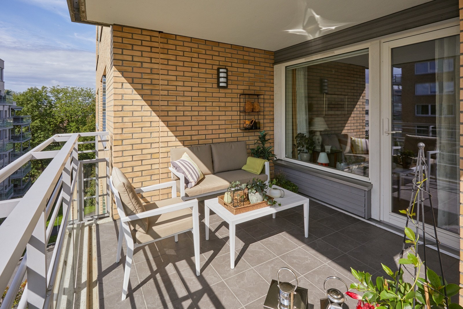 Balkongen er overbygget, har fliser på gulv og rekkverk av stålprofiler og glass. Det er også montert utebelysning og stikkontakt. Galleribilde