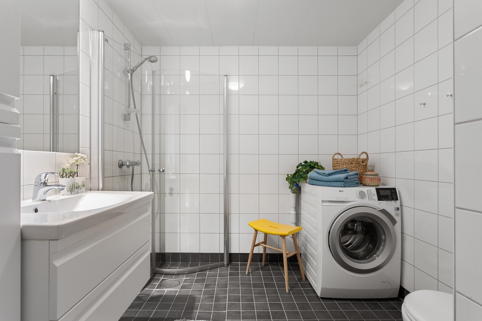Baderommet fra 2009 har mørke fliser på gulv med gulvvarme, lyse fliser på veggene og lampe kombinert med downlights i himlingen. Mekanisk avtrekksventil plassert i himling, styres via kjøkkenventilator. Galleribilde