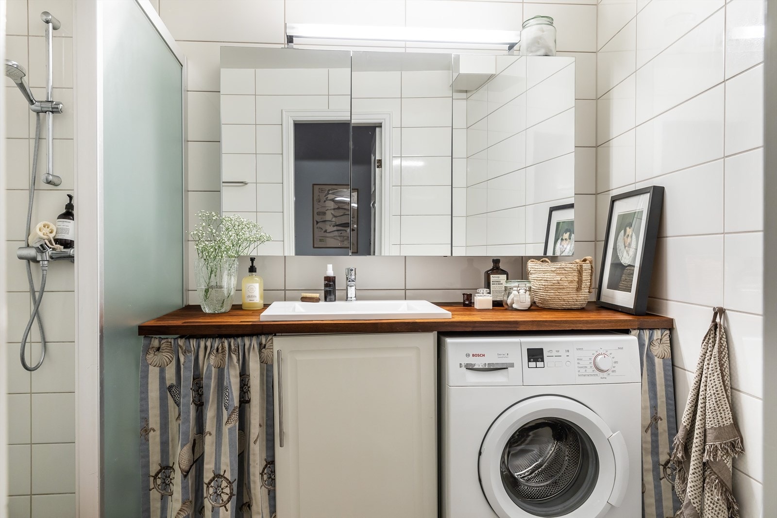 Det er lagt fliser på betong og sluk i plast, baderomsinnredning bestående av benkeskap med profilerte fronter og veggskap med speilfronter Galleribilde