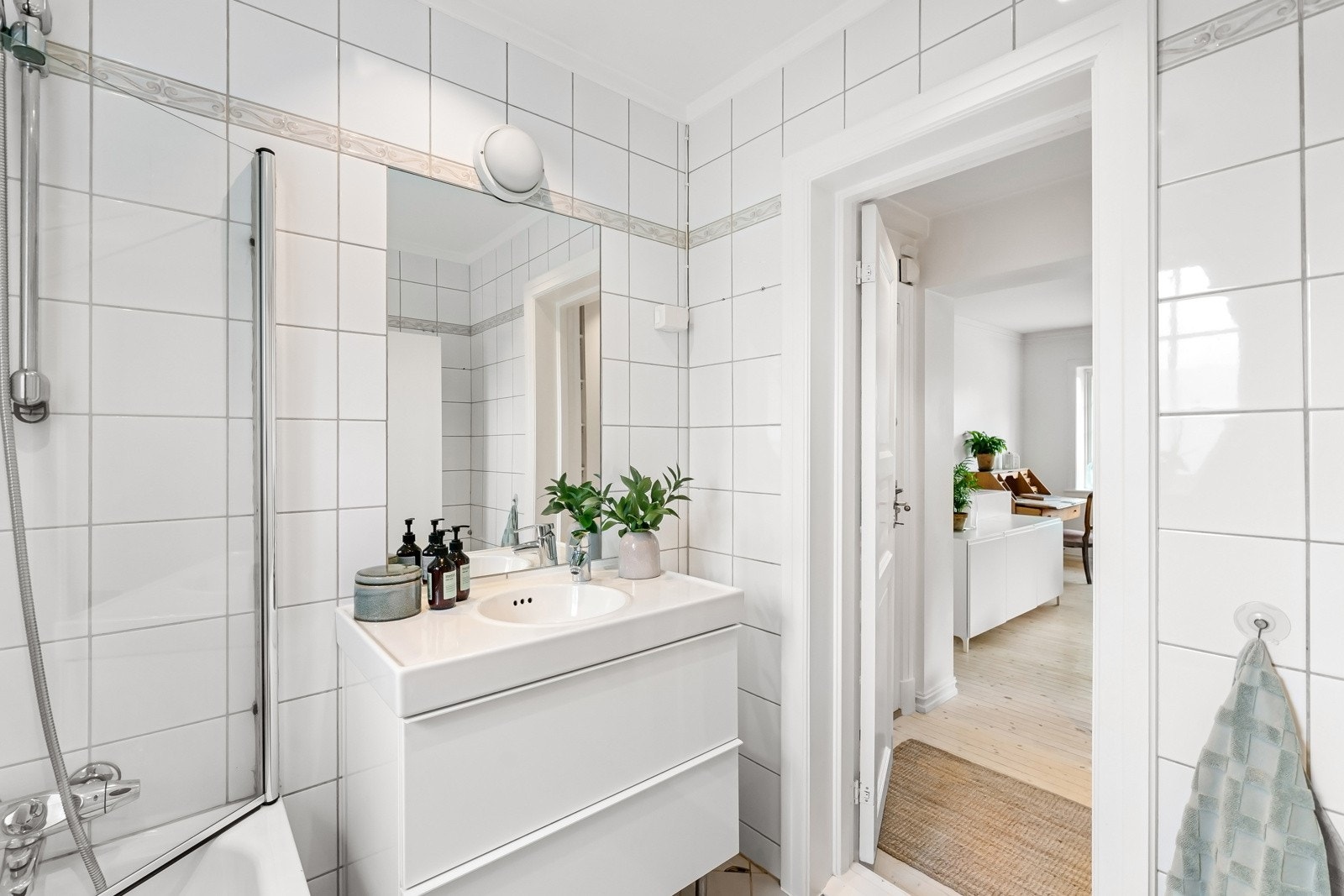 Gulvet har beige fliser, veggene har hvite fliser og det er rutemønster rundt badekaret. Det er varme i gulv og downlights i himling. Galleribilde