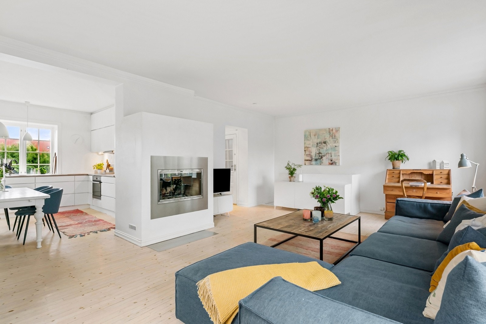 Det er god plass til sofagruppe i stuesonen og spisebord i overgangen til kjøkkenet. En lekker peis med glassfront og omramming i stål, skaper et lunt blikkfang i rommet. Galleribilde