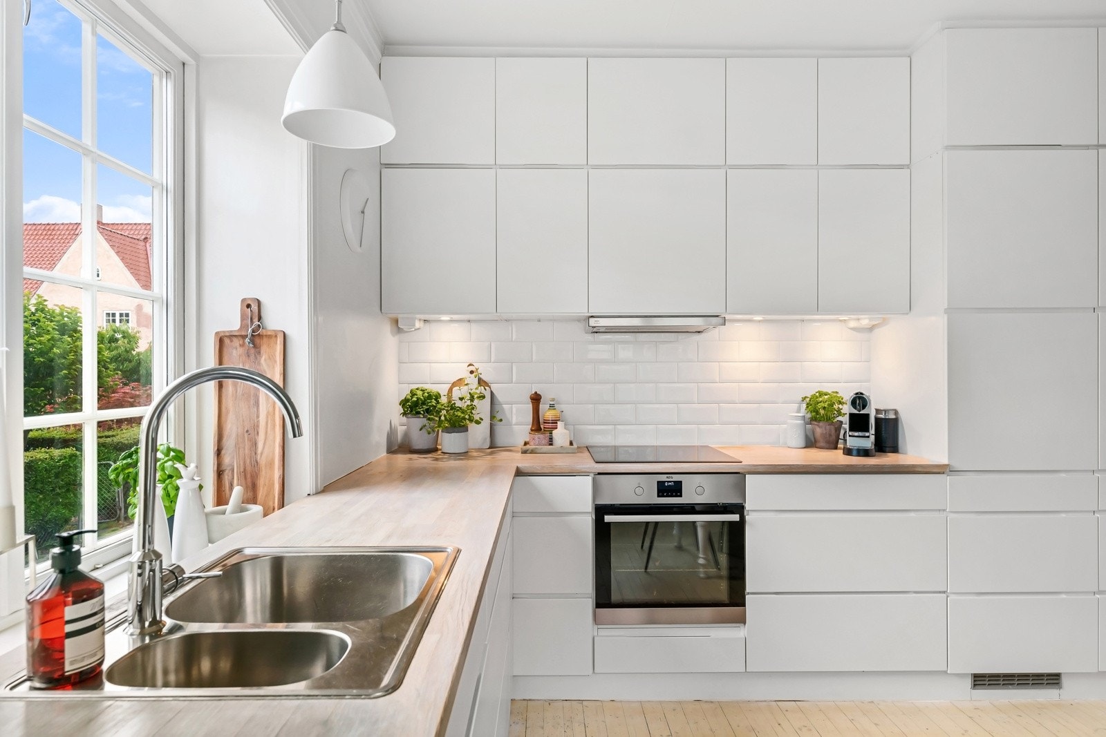 Innredningen er plassert langs to sider med vindu over vaskebenken og hvite metrofliser over kokesone. Galleribilde