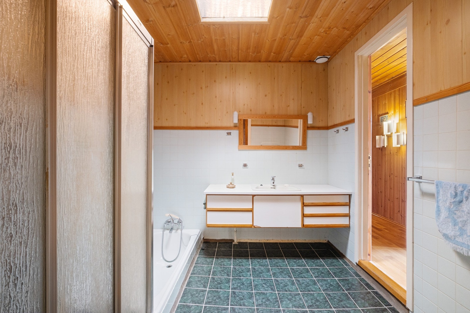 Baderommet har fliser på gulv og på deler av veggene, og innredningen består av vegghengt servantskap med ovenpåliggende servant og speil. Galleribilde