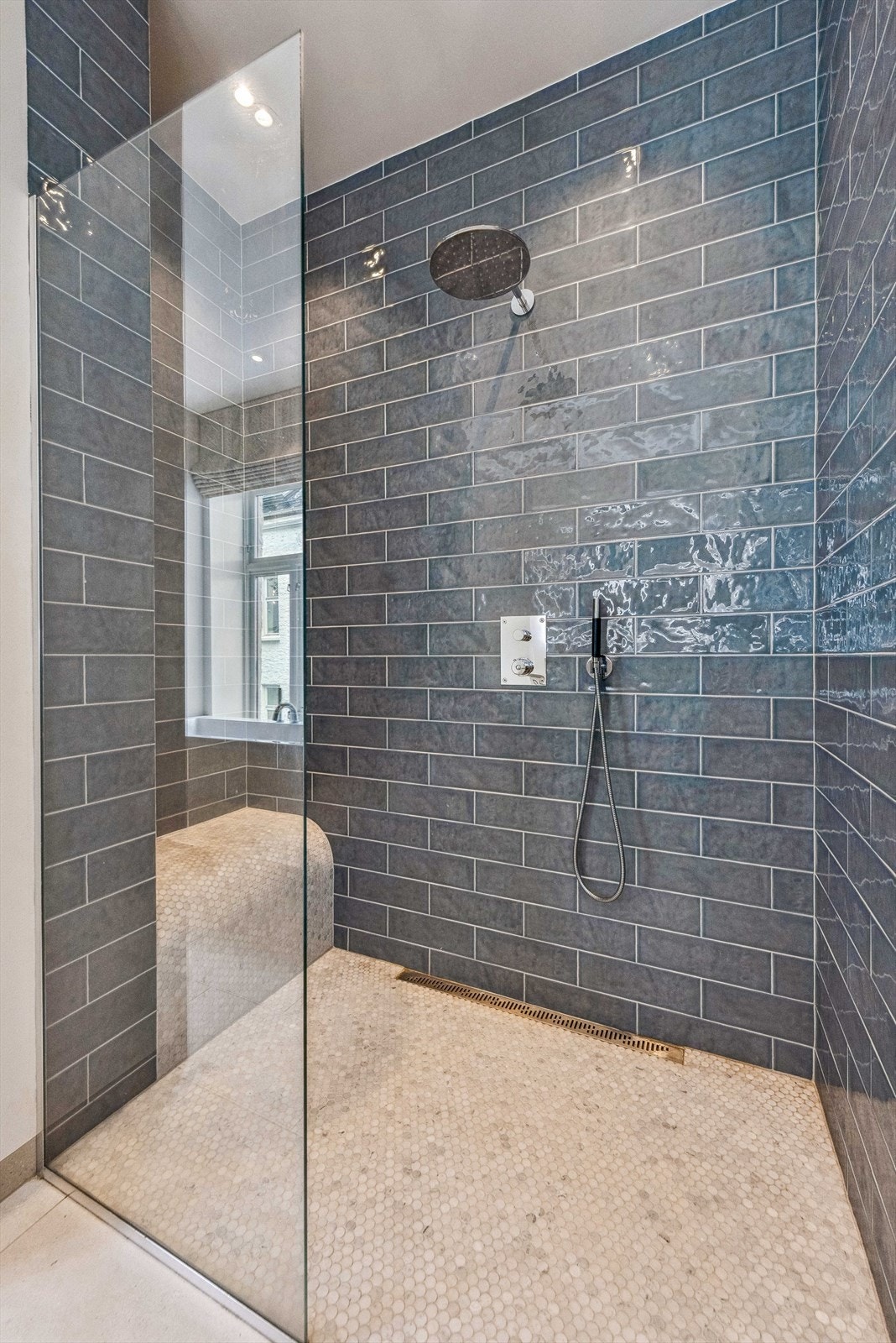 Videre har badet en stor dusjnisje med dør/vegg i herdet glass og veggmontert toalett. Galleribilde