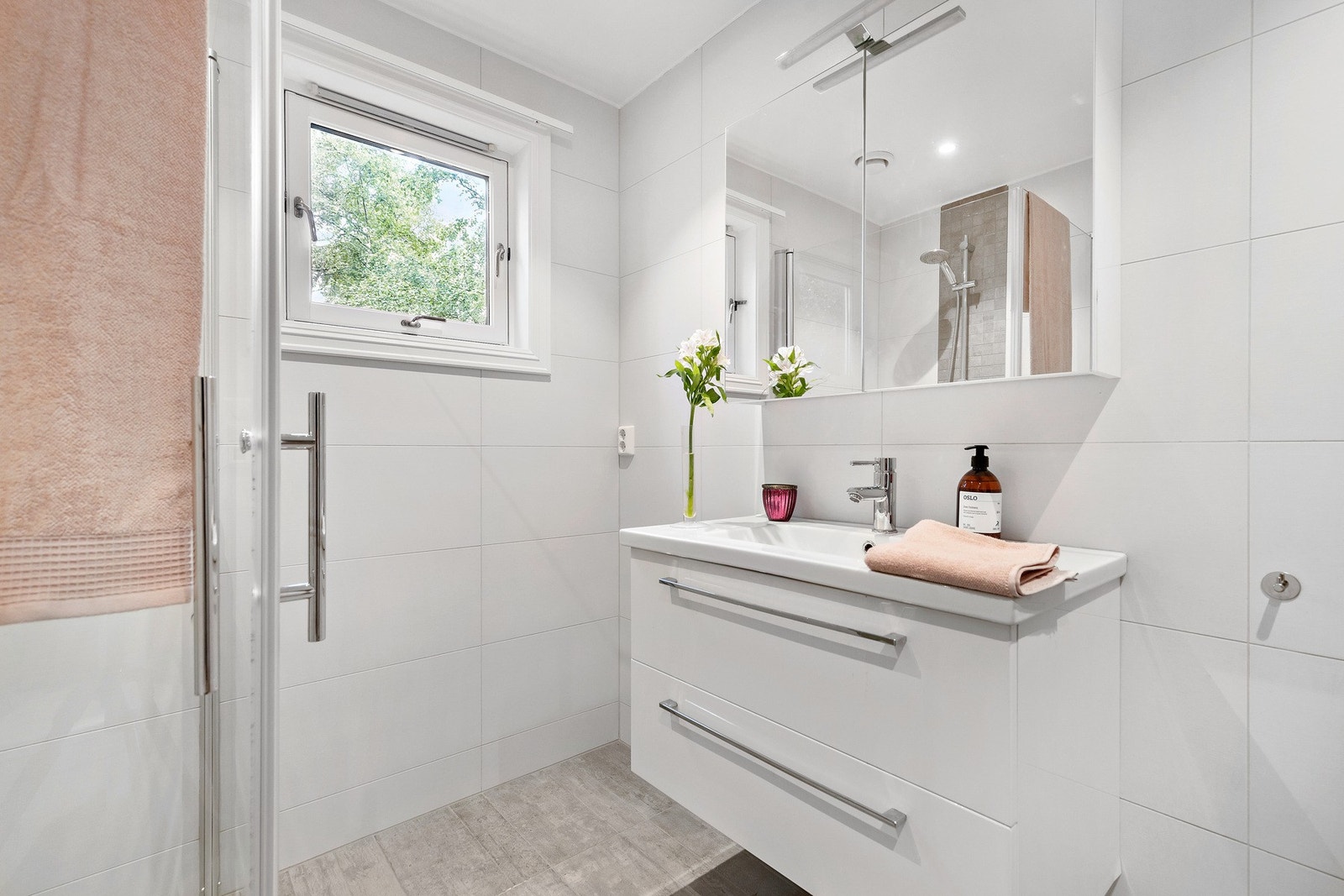 Badet består av dusjhjørne, vegghengt toalett, opplegg for vaskemaskin og moderne baderomsinnredning. Galleribilde