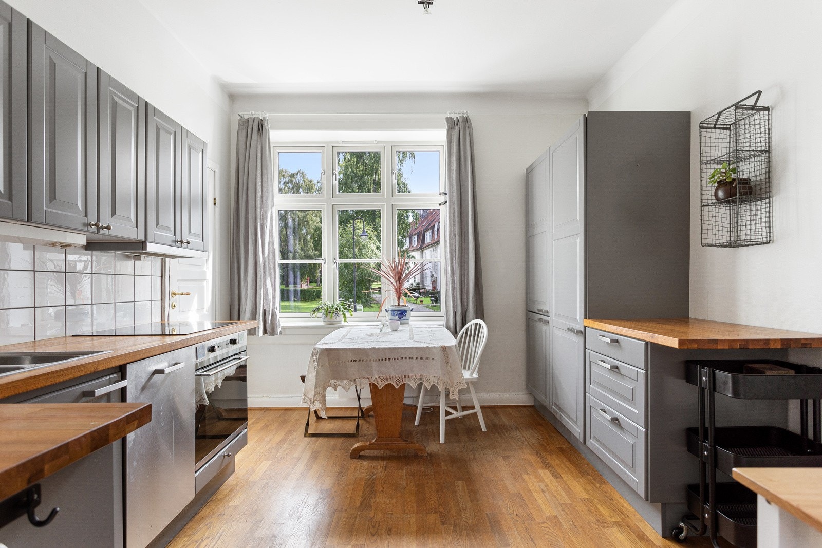 Pen og tidløs kjøkkeninnredning med god skap- og benkeplass. Innredningen har grå profilerte fronter og benkeplate av tre med nedfelt oppvaskkum. Praktisk med fliser i benkeryggen og belysning under overskapene. Galleribilde