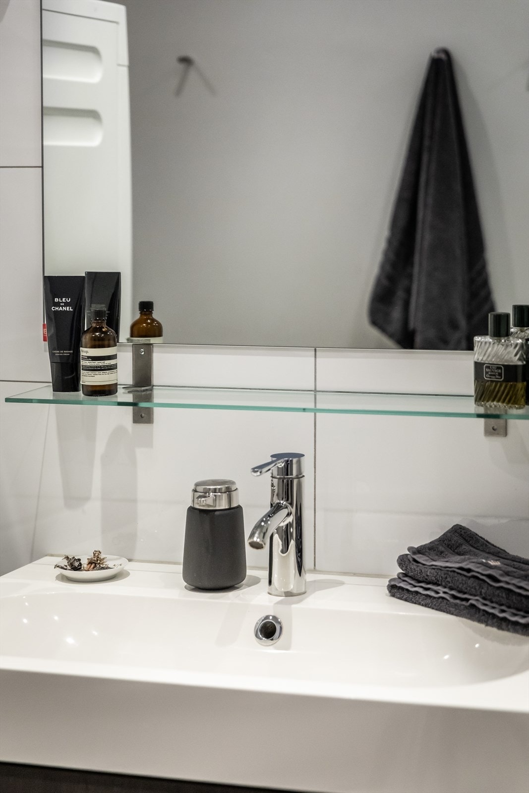 Pent og lyst baderom med vegghengt servantskap med skuffer, toalett, oppbevaringsskap og dusjhjørne med glassdører. Galleribilde