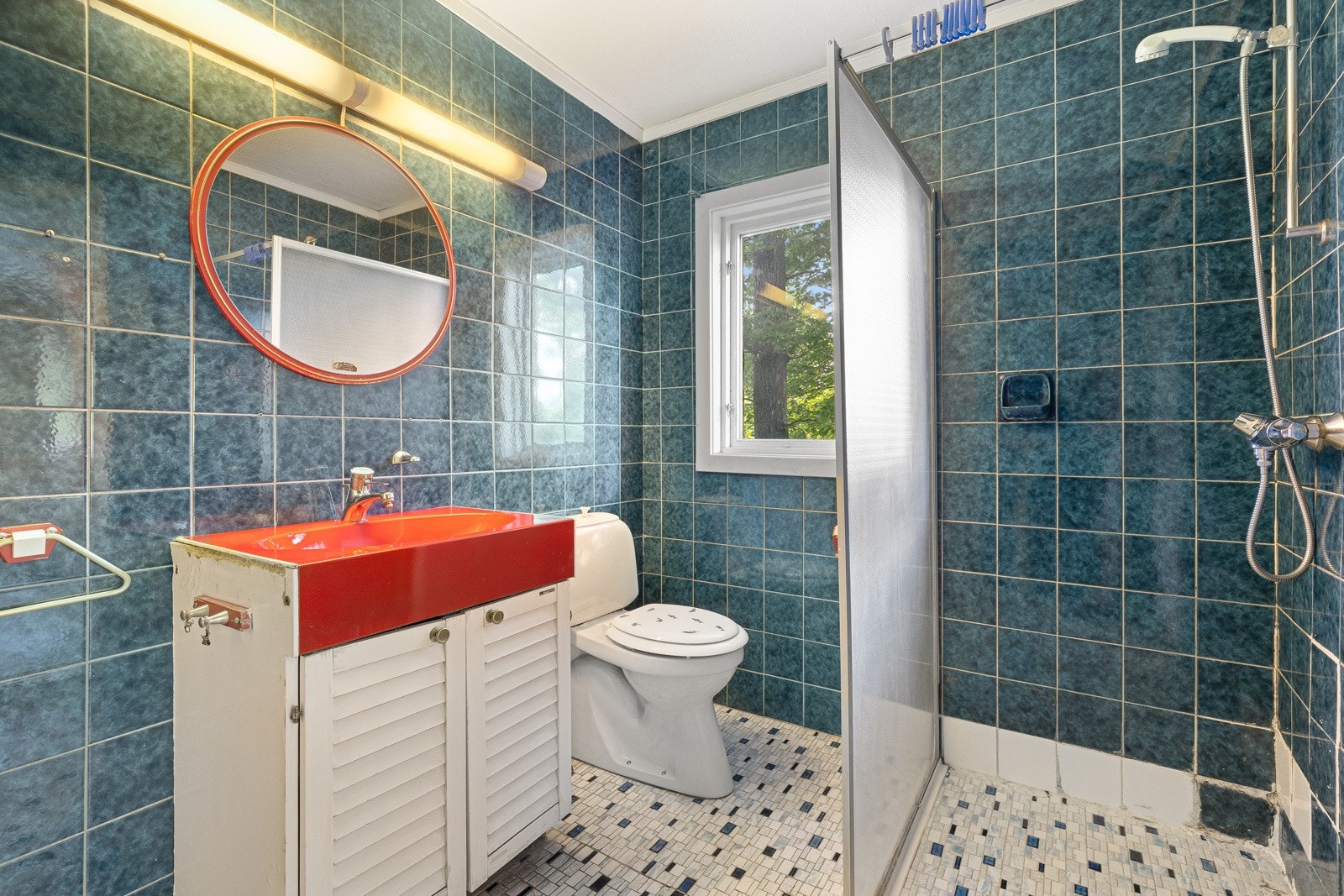 Badet i første etasje er innredet med gulvstående klosett, servant med underskap og dusjhjørne med vegg i plast. Galleribilde