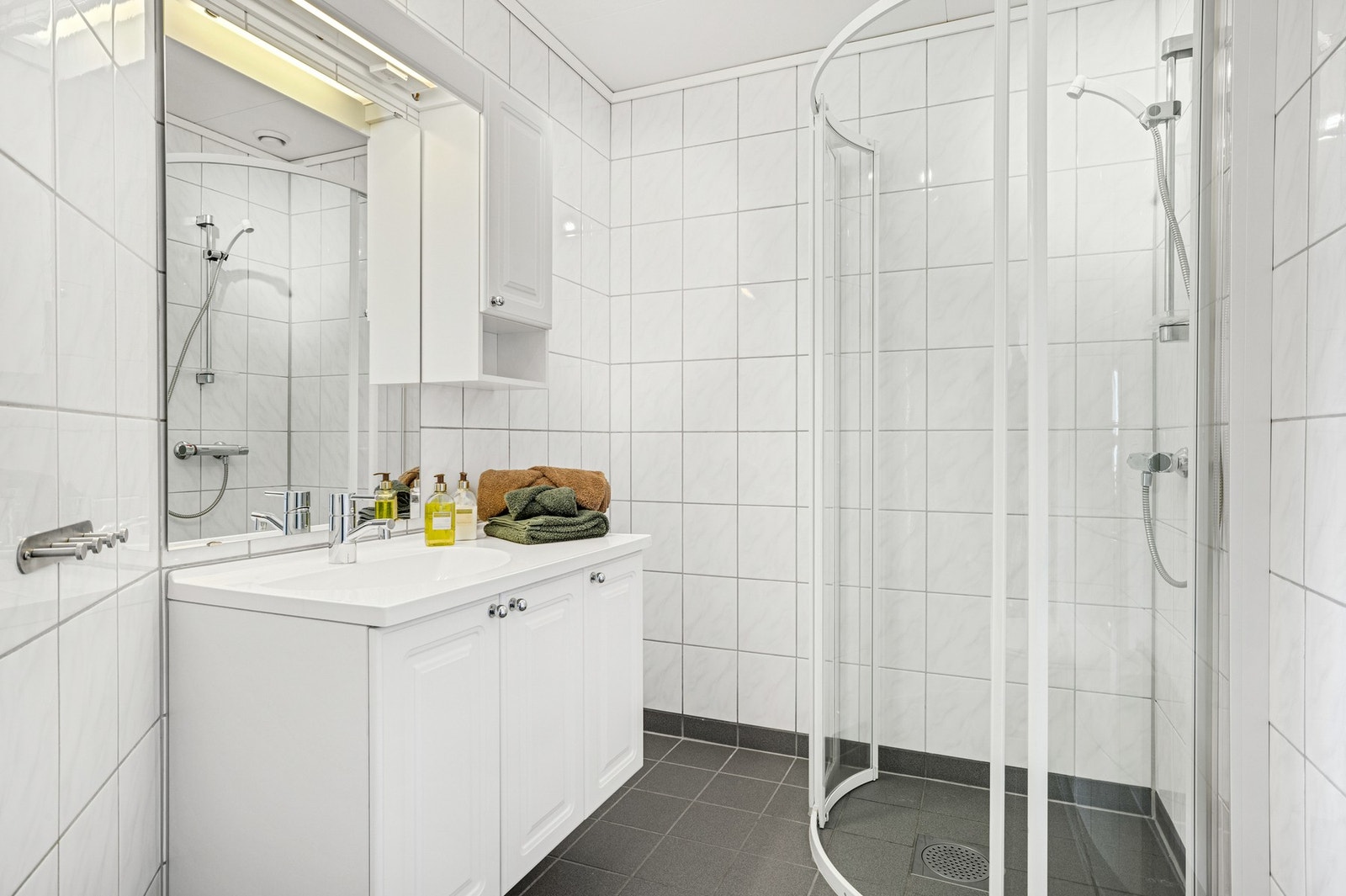 Flislagt bad i 1. etasje med en praktisk dusjnisje og vegghengt innredning. Badet er på ca. 4 kvm. Galleribilde