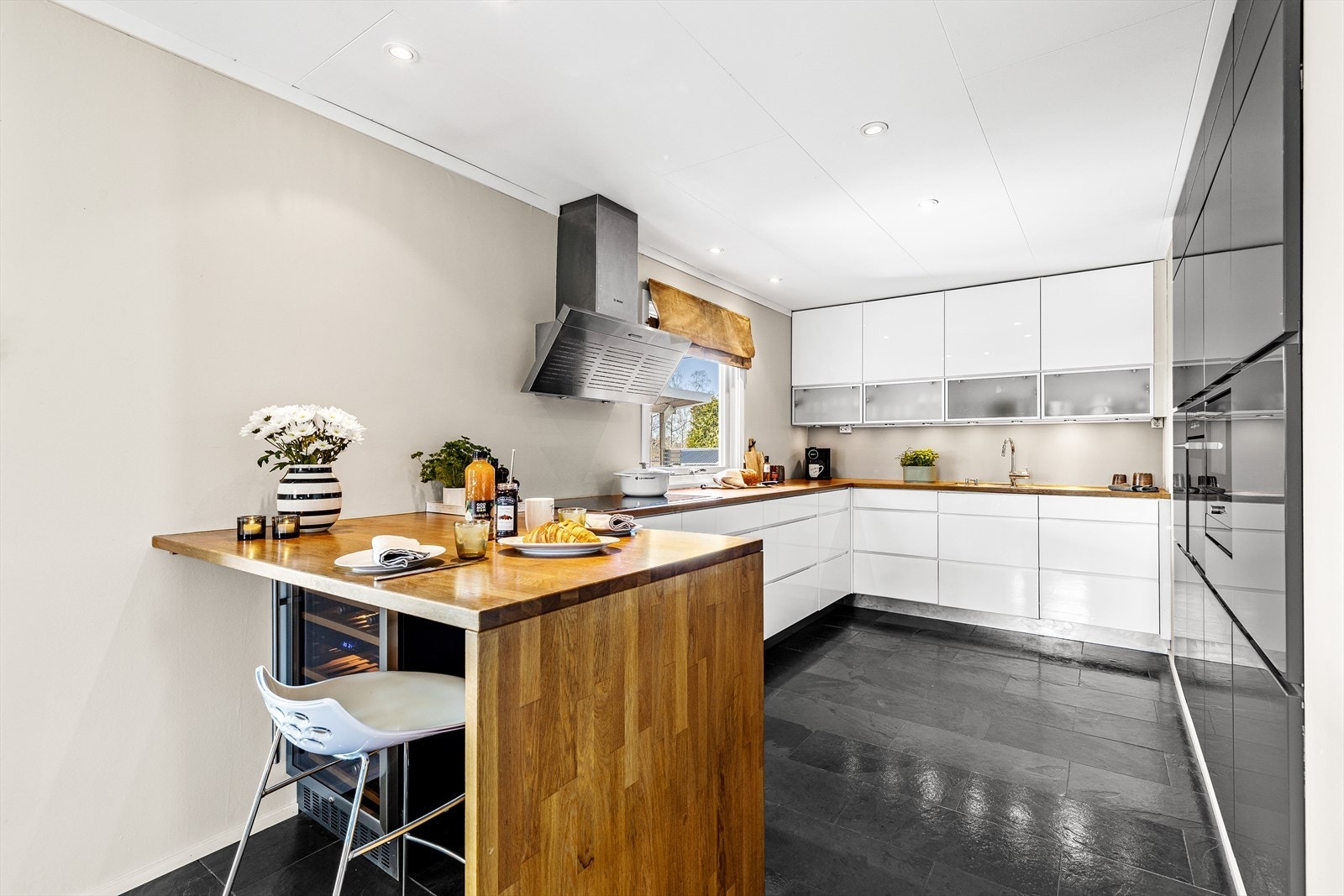 Ved enden av kjøkkenbenken er det sitteplass for flere. Og under benken er det montert vinskap Galleribilde