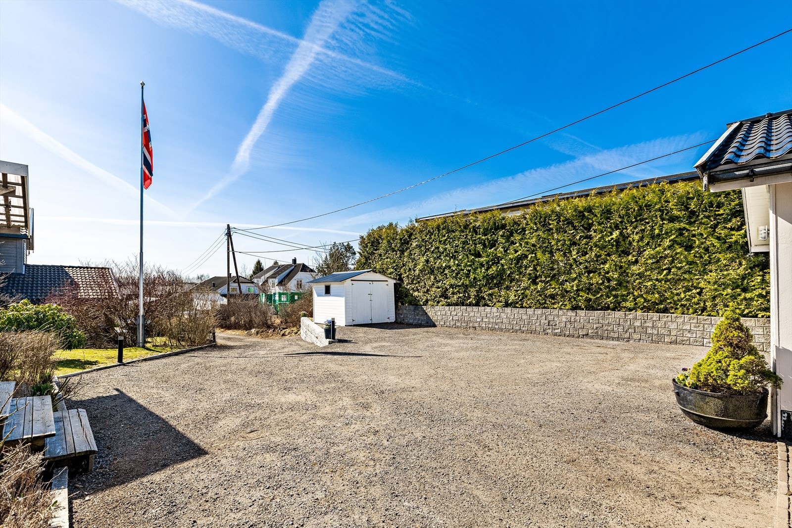 Gårdsplassen er pent opparbeidet med dels slipe-asfalt og dels steinlagt med belegningstein. Her er en redskapsbod, støttemur av granitt, mini-støttemur, hekker og beplantning Galleribilde