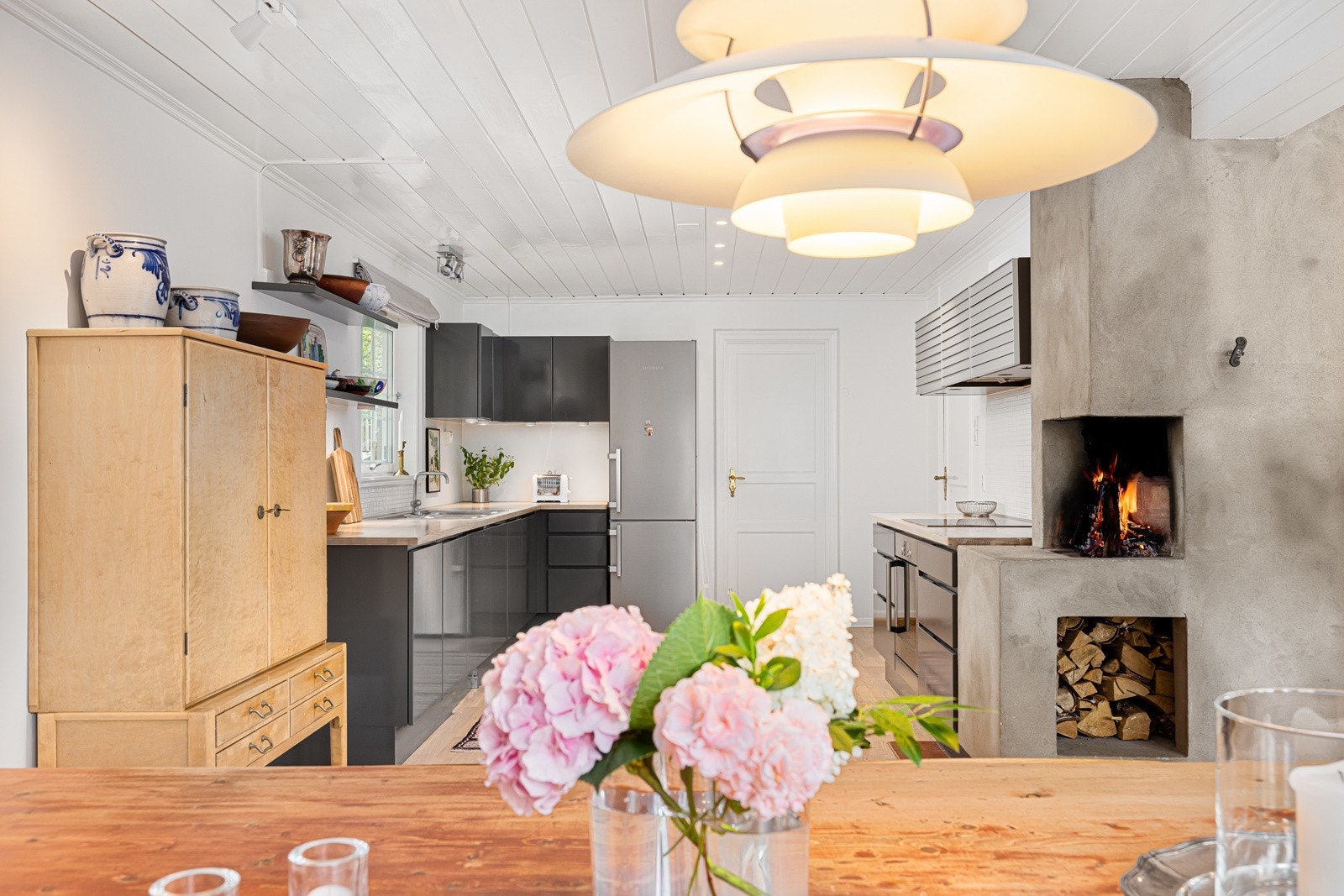 Kjøkkenet har heltre benkeplate med nedfelt vask og skyllekum. Nedfelt glasskeramisk koketopp i benkeplate og ventilator på vegg. Galleribilde