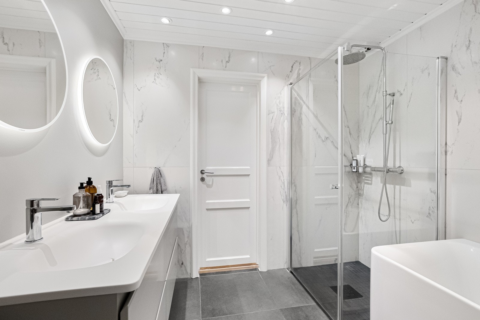 Badet inneholder dusjhjørne, innmurt badekar og to servanter. Galleribilde