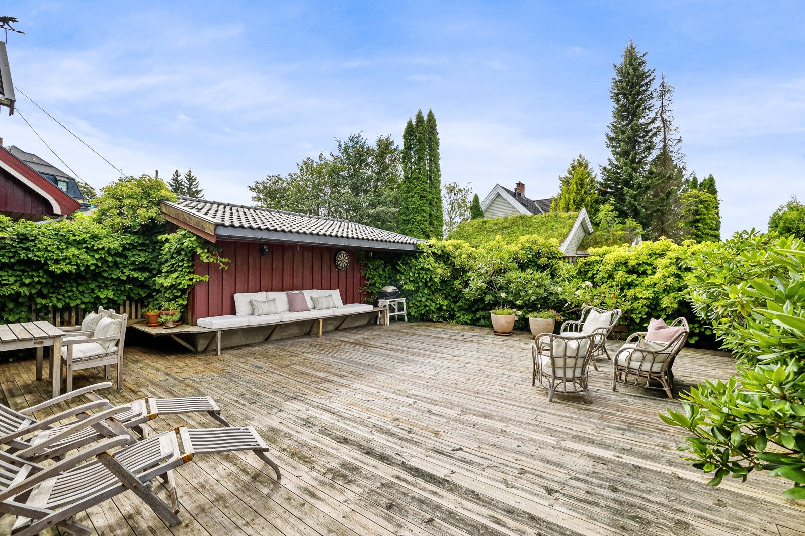 Romslig og vedlikeholdsfri hage/terrasse, omkranset av busker og klatreplanter etablert i regi av landskapsarkitekt. Galleribilde