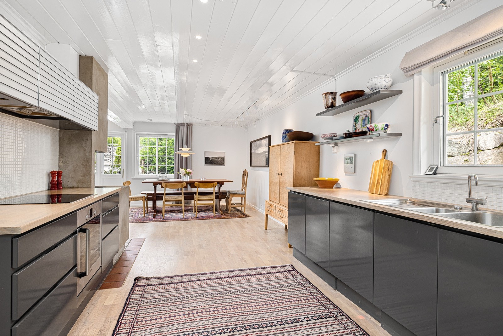 Kjøkkeninnredning med gråmalte glatte fronter har en innholdsrik innredning og romslig arbeidsbenk. Galleribilde