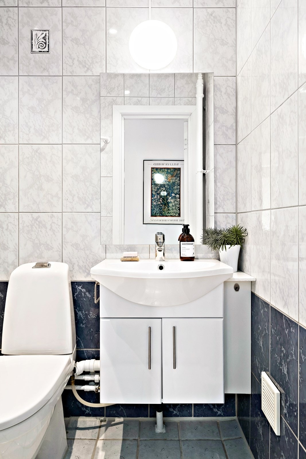 Flislagt bad med servantskap, dusjkabinett og gulvmontert toalett Galleribilde