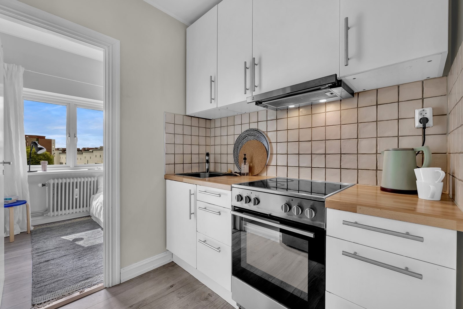 Hyggelig og praktisk, separat kjøkken fra IKEA. Innredningen består av hvite malte fronter, fliser over benkeplate og laminert benkeplate. Galleribilde