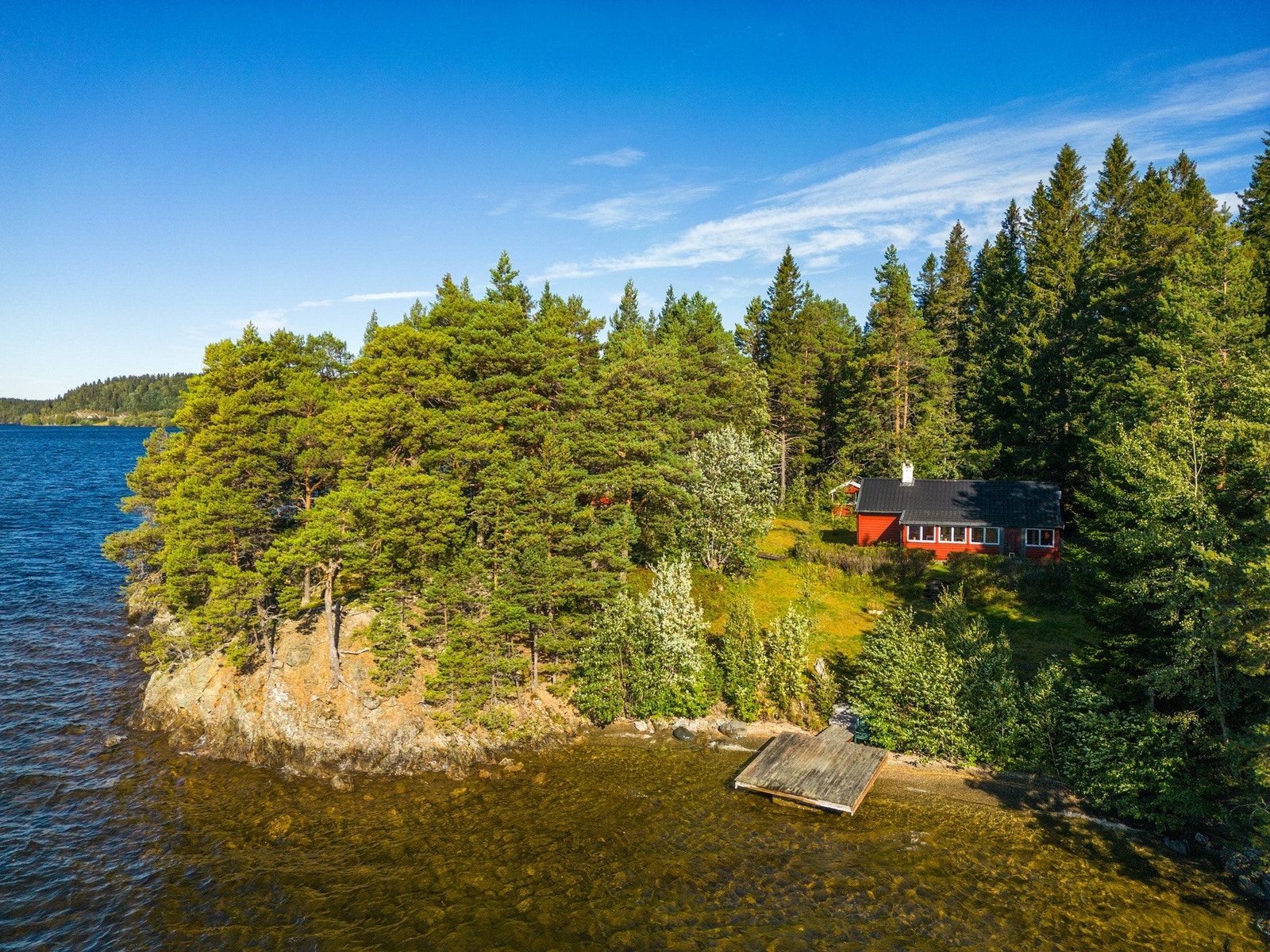 Hovedhytten ligger i en lysning på tomten og har utsikt ut mot vannet. Galleribilde