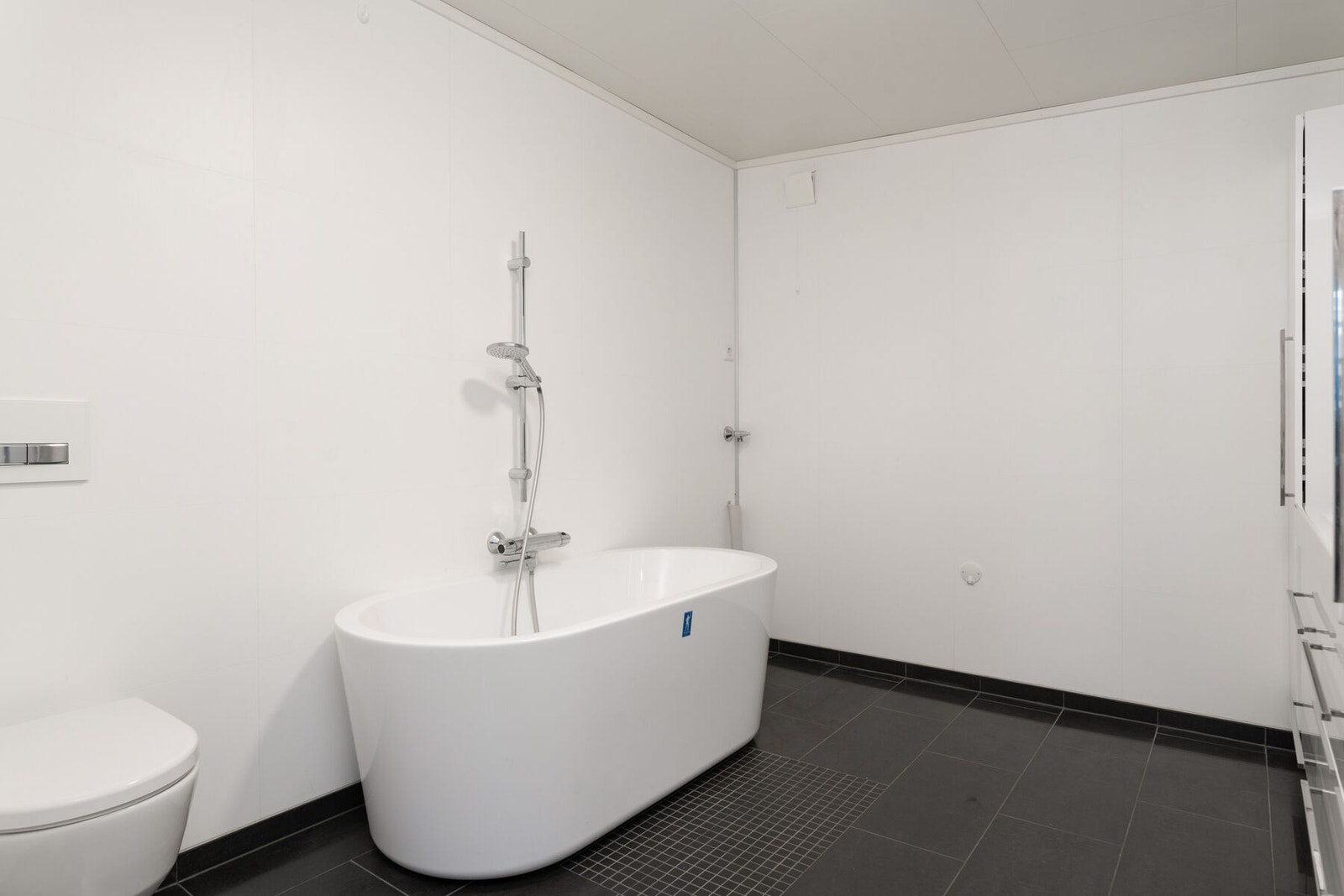 Badet er utstyrt med badekar, vegghengt toalett og servantmøbler med mye lagringsplass Galleribilde