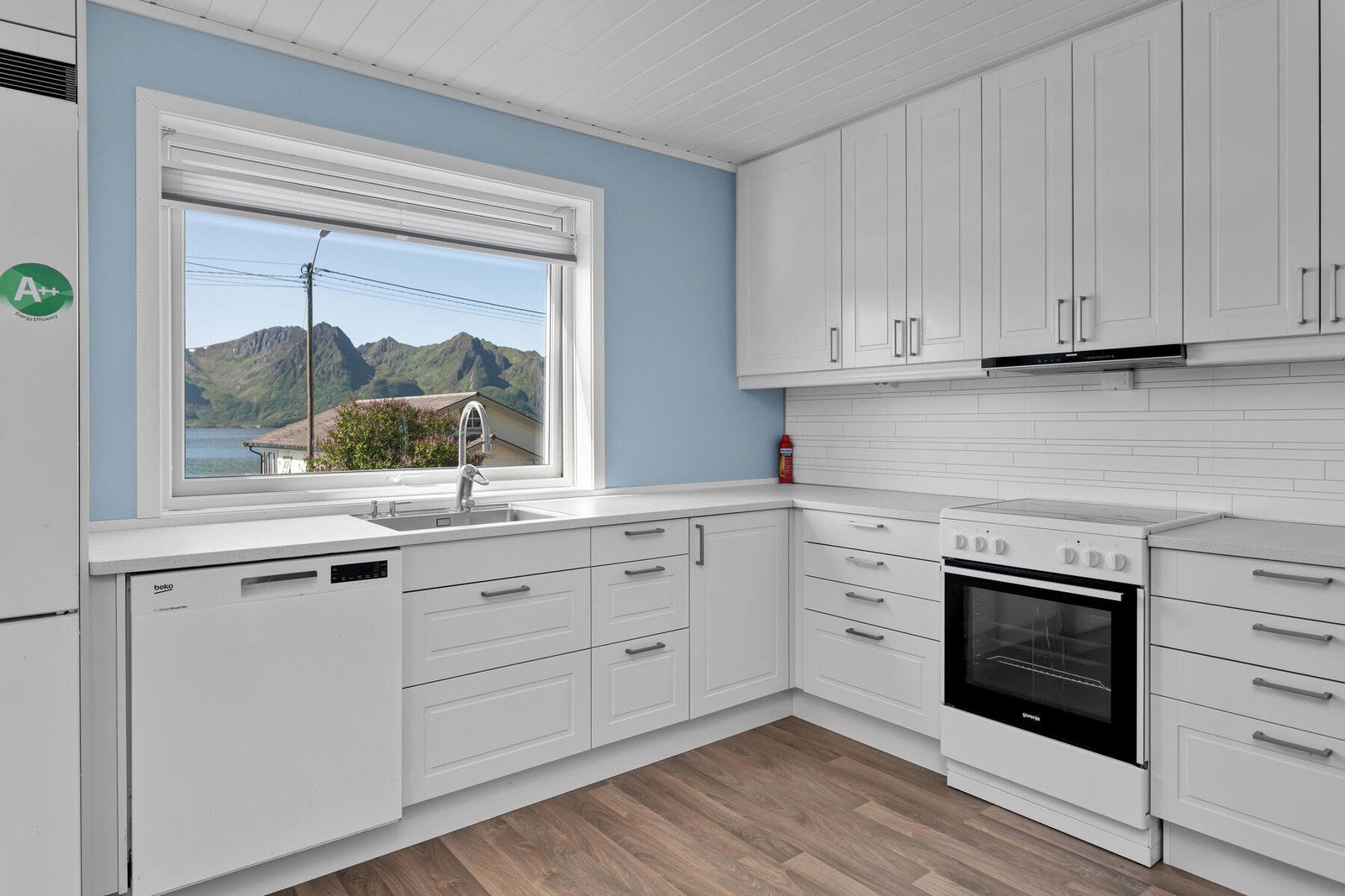 Klassisk, pent kjøkken med hvite profilerte fronter og frittstående hvitevarer Galleribilde