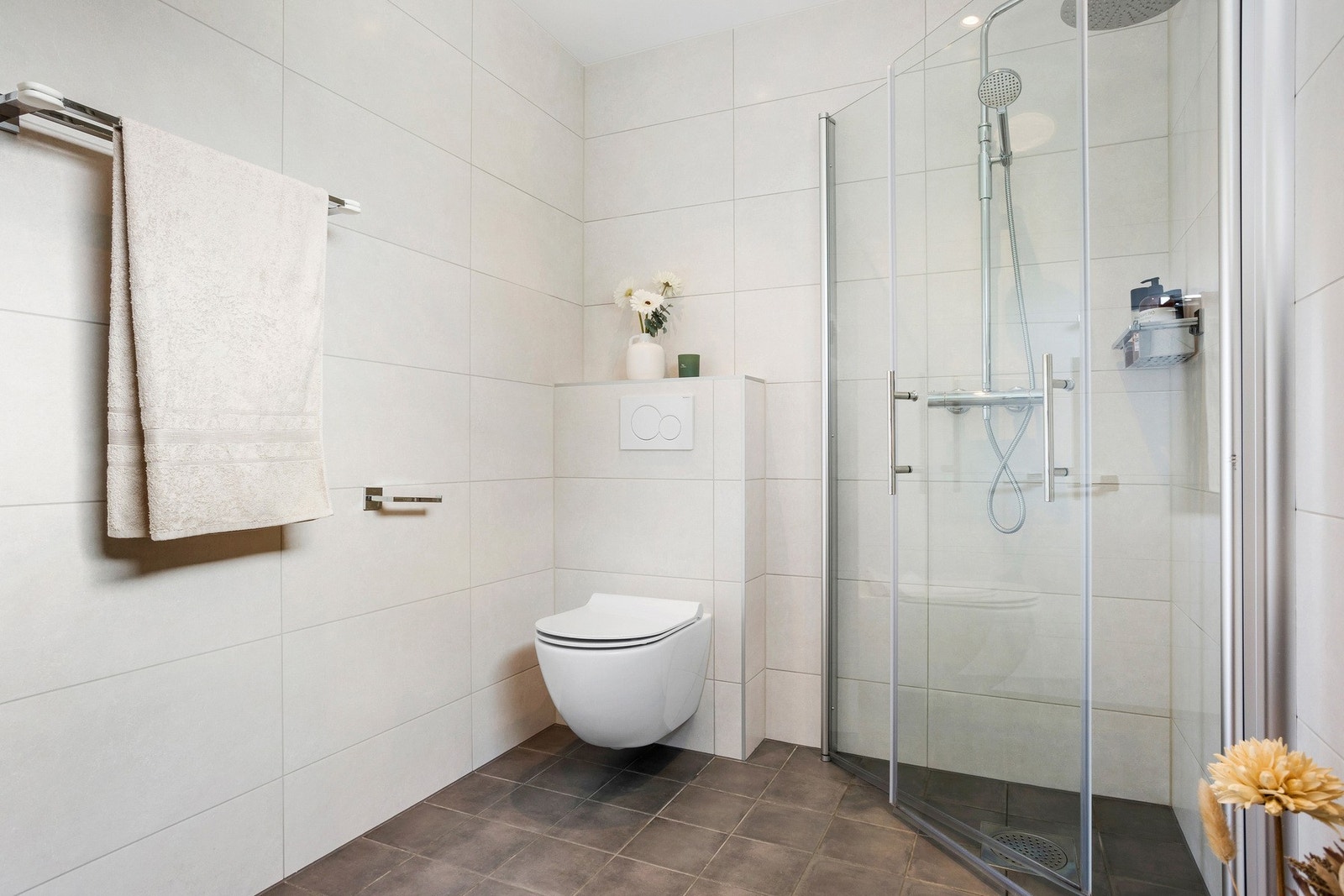 Badet er utstyrt med innfellbare dusjdører i glass som gir en stor dusjsone og et moderne vegghengt toalett Galleribilde