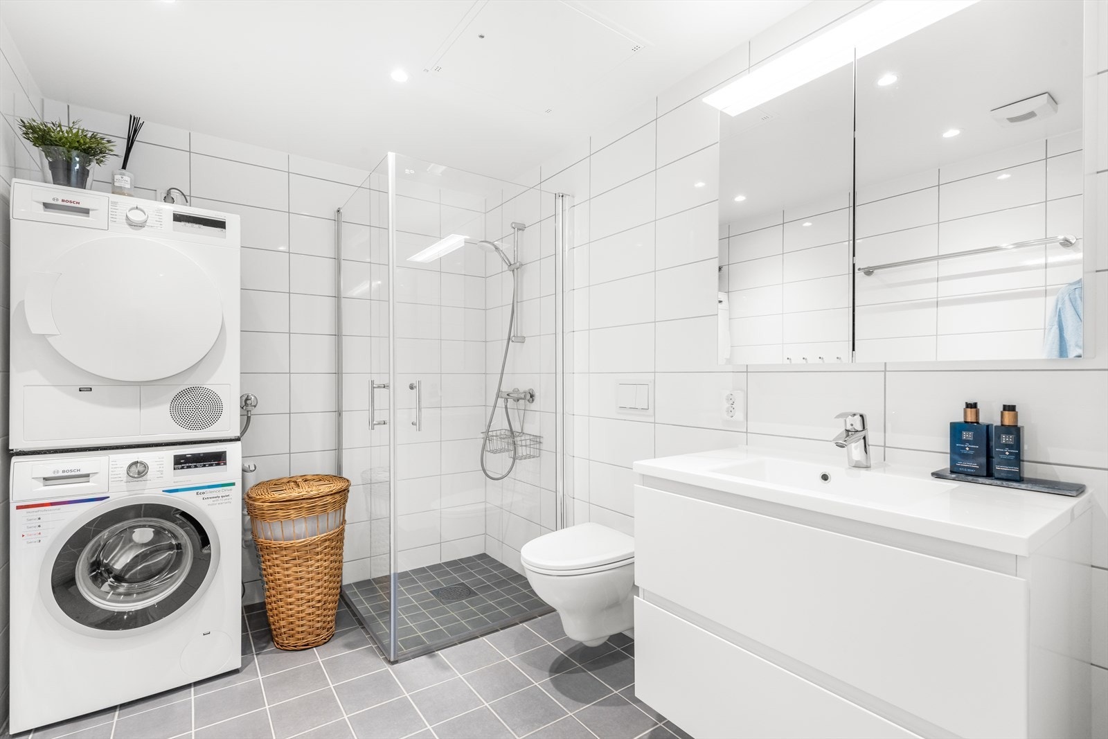 Badet er utstyrt med et dusjhjørne med
glassdører, et vegghengt toalett, en servantinnredning og opplegg for både vaskemaskin og tørketrommel. Galleribilde