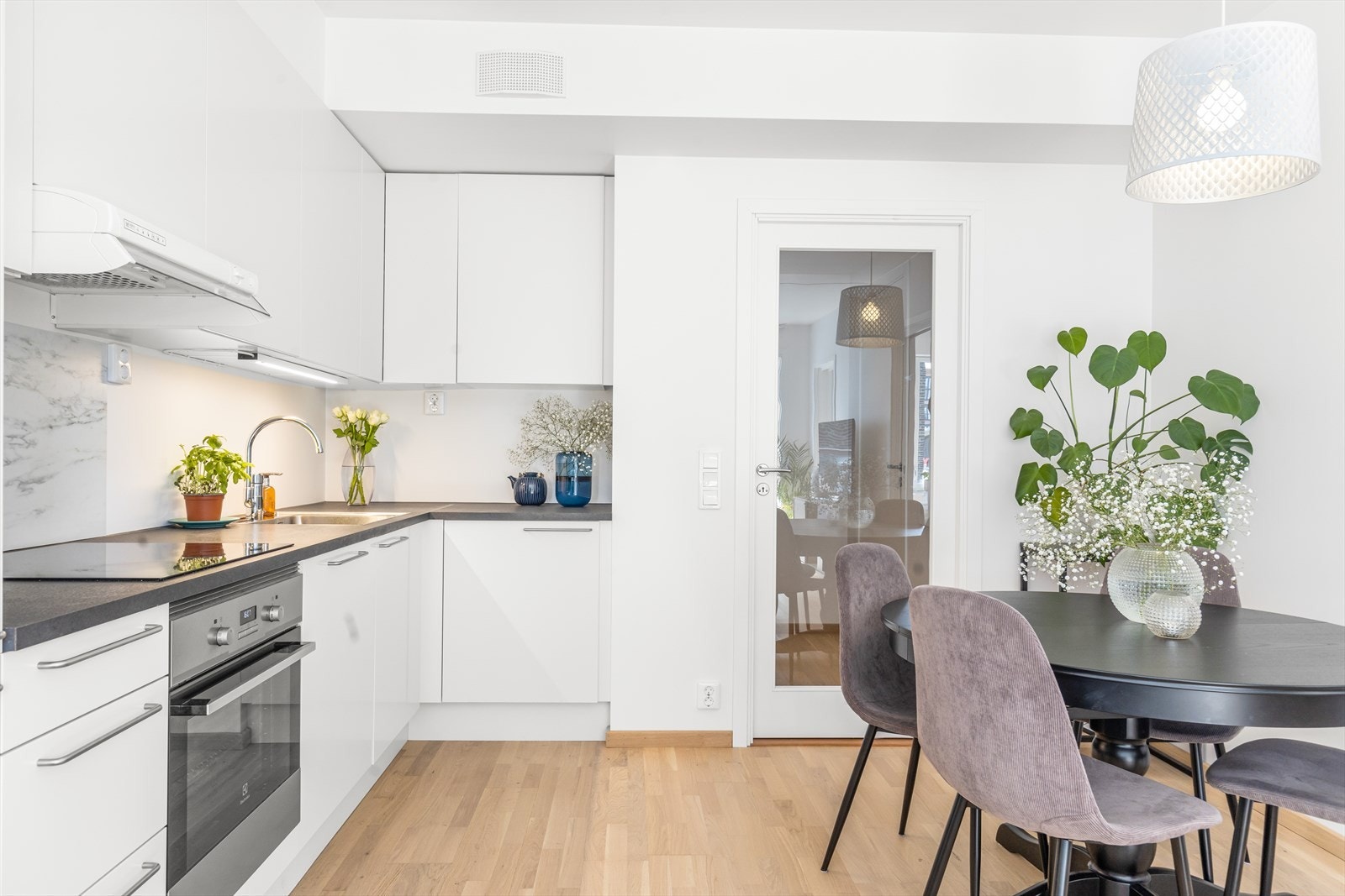 Lys og stilren kjøkkeninnredning med slette fronter og laminert benkeplate med nedfelt stålkum. Galleribilde