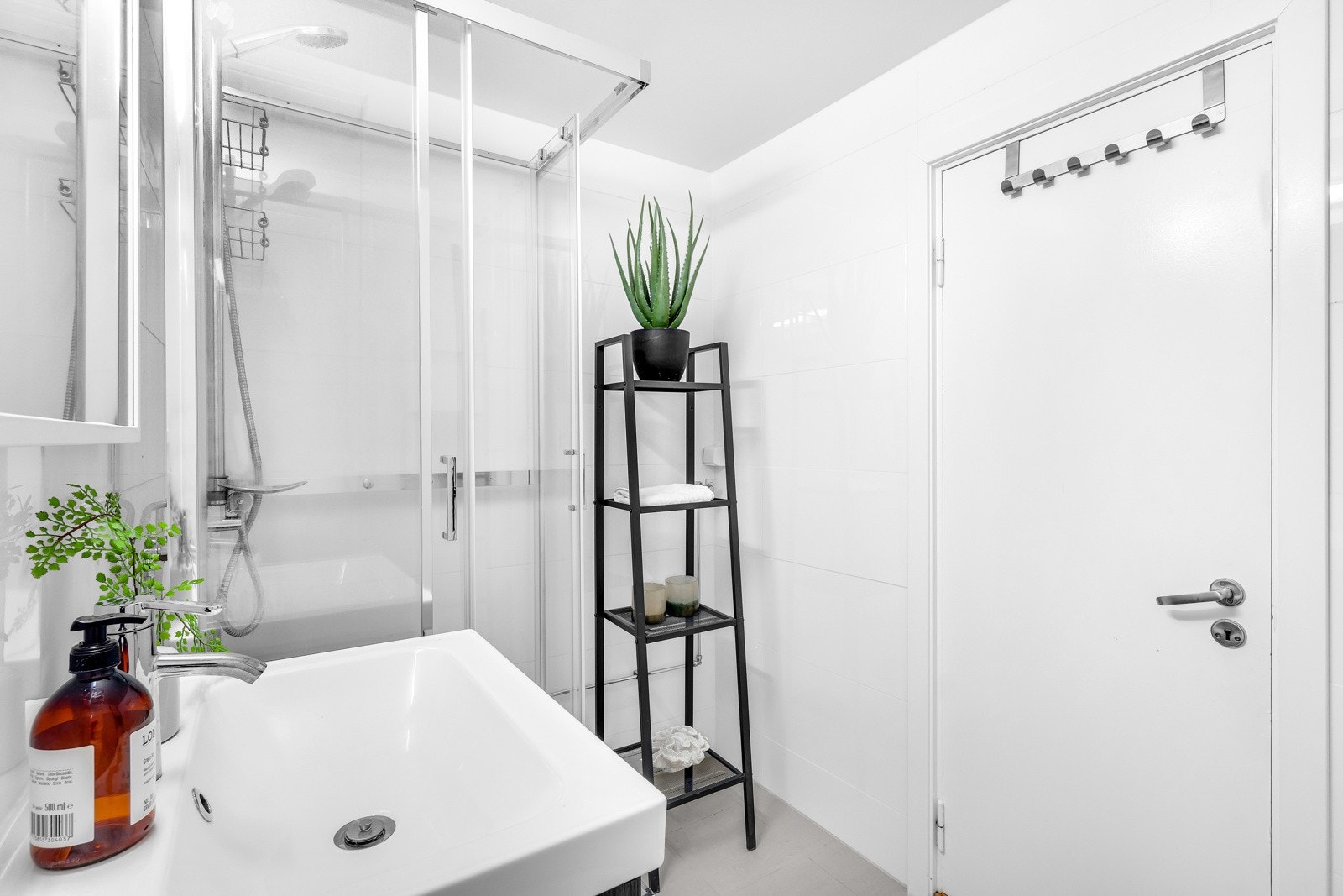 Badet er utstyrt med heldekkende servantskap med glatte fronter, speil over servant med lysarmatur, gulvmontert klosett, dusjkabinett med skyvedører, og opplegg for vaskemaskin samt gulvvarme Galleribilde