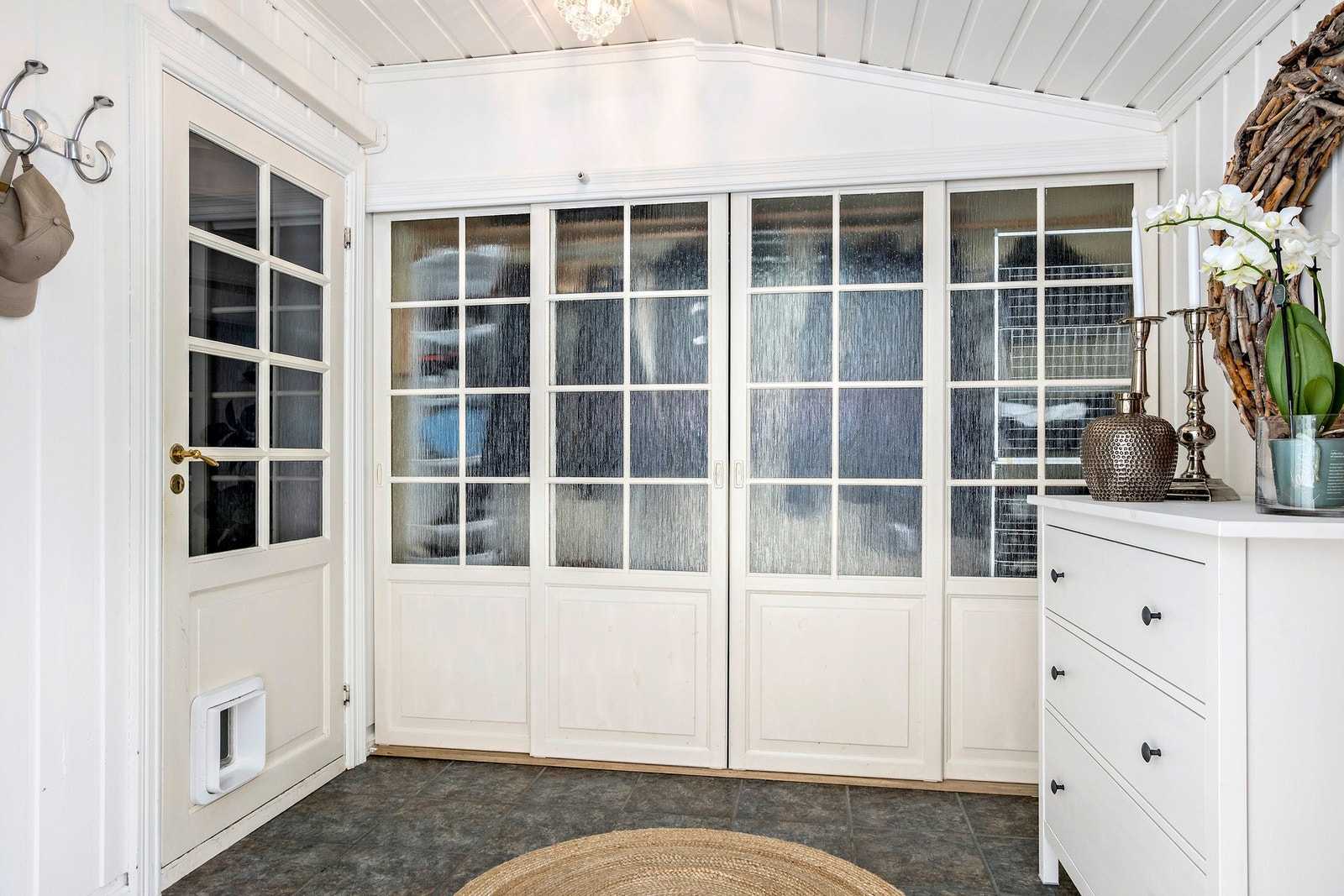 Flislagt entré med varmekabler i gulv og skyvedørsgarderobe. For katten i huset er det luke både i gang og ved inngangsdøren. Galleribilde