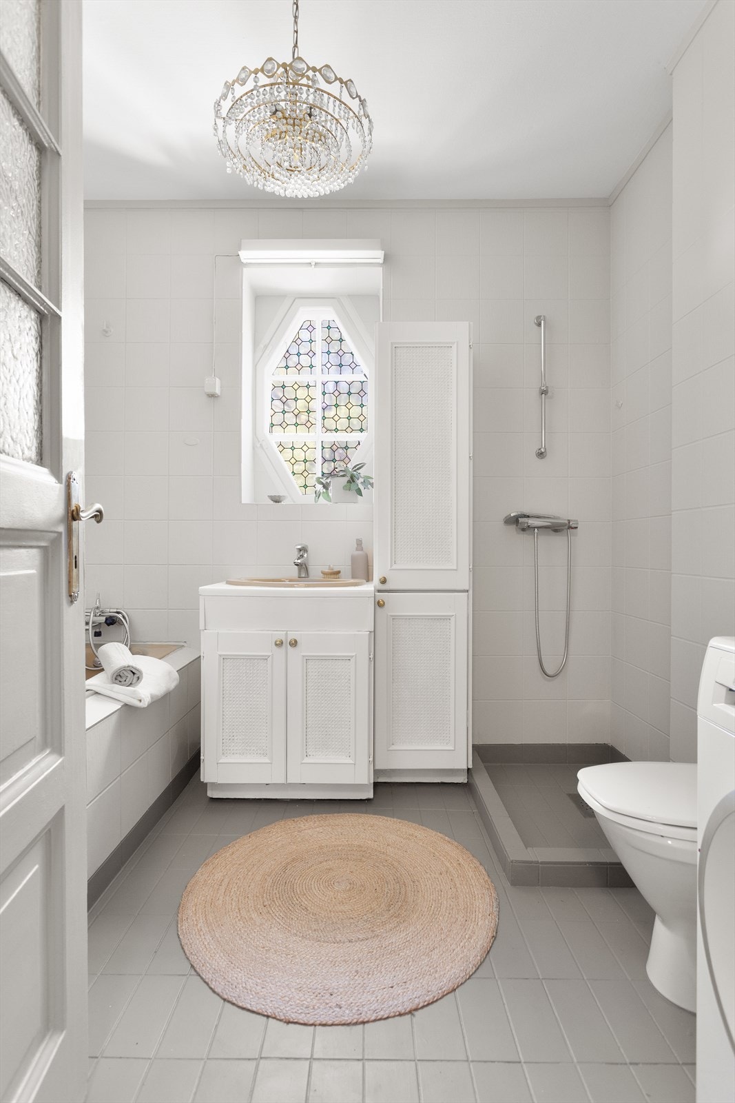 Badet i 1.etasje ligger i fin tilknytning til entréen. Badet er eldre, og består av wc, servant med skap under, innmurt badekar og dusj i hjørne, samt opplegg for vaskemaskin. Galleribilde