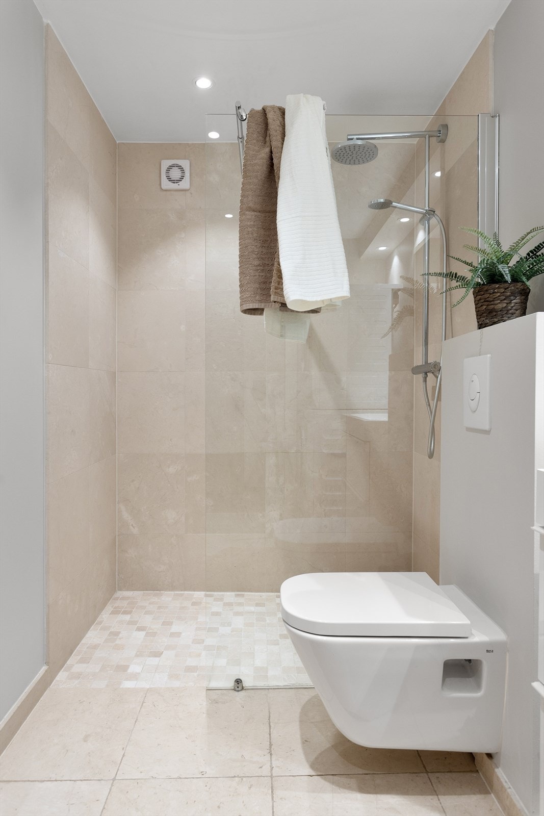 Badet har eksklusive natursteinsfliser fra Fired Earth og er utstyrt med veggmontert wc, servant med skuffer under og dusj med glassvegg. Galleribilde