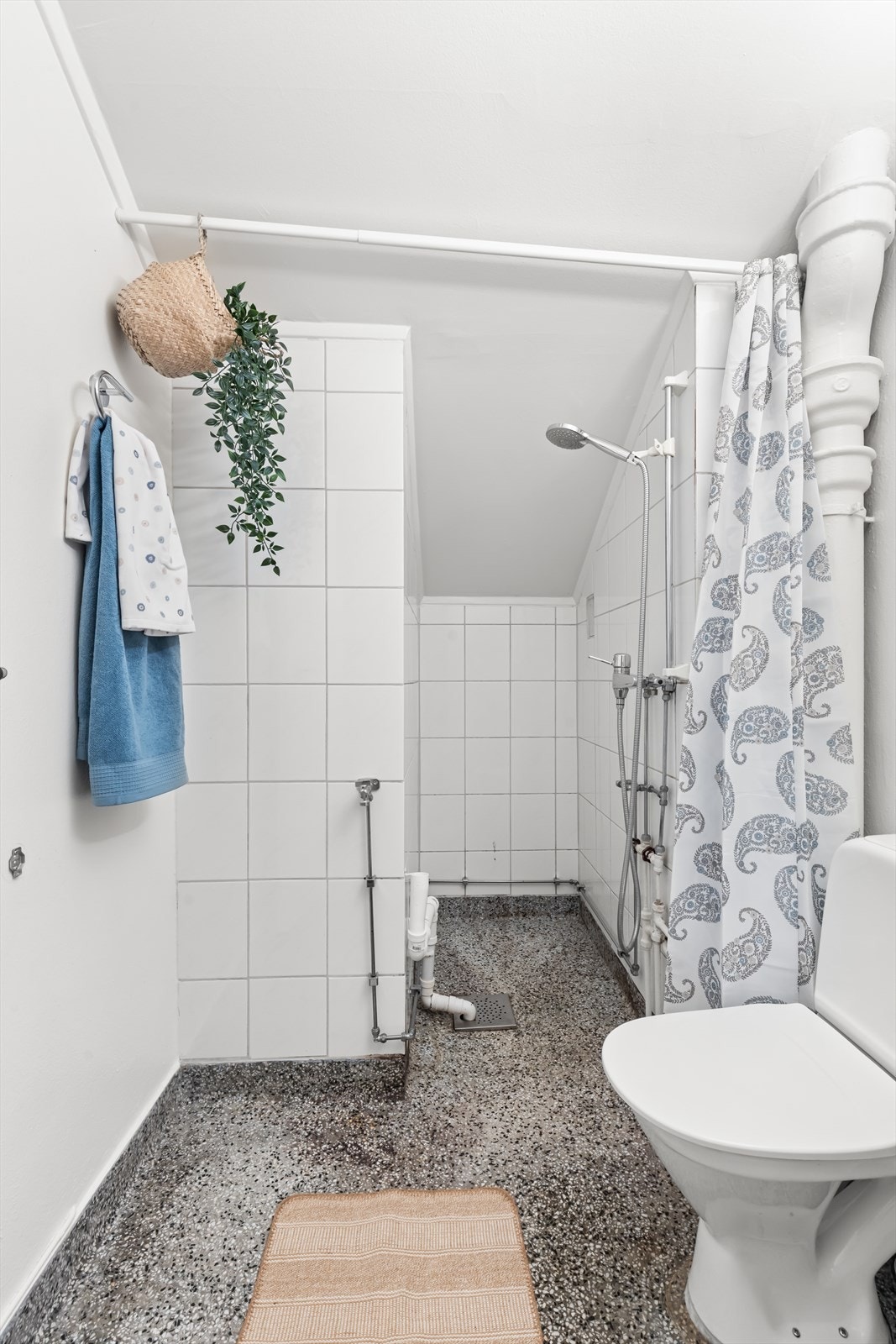 Baderom med terrassestøp på gulv, hvite fliser på vegg og pusset og malt overflate på vegg. Baderommet har behov for oppgradering. Les vedlagt tilstandsrapport. Galleribilde